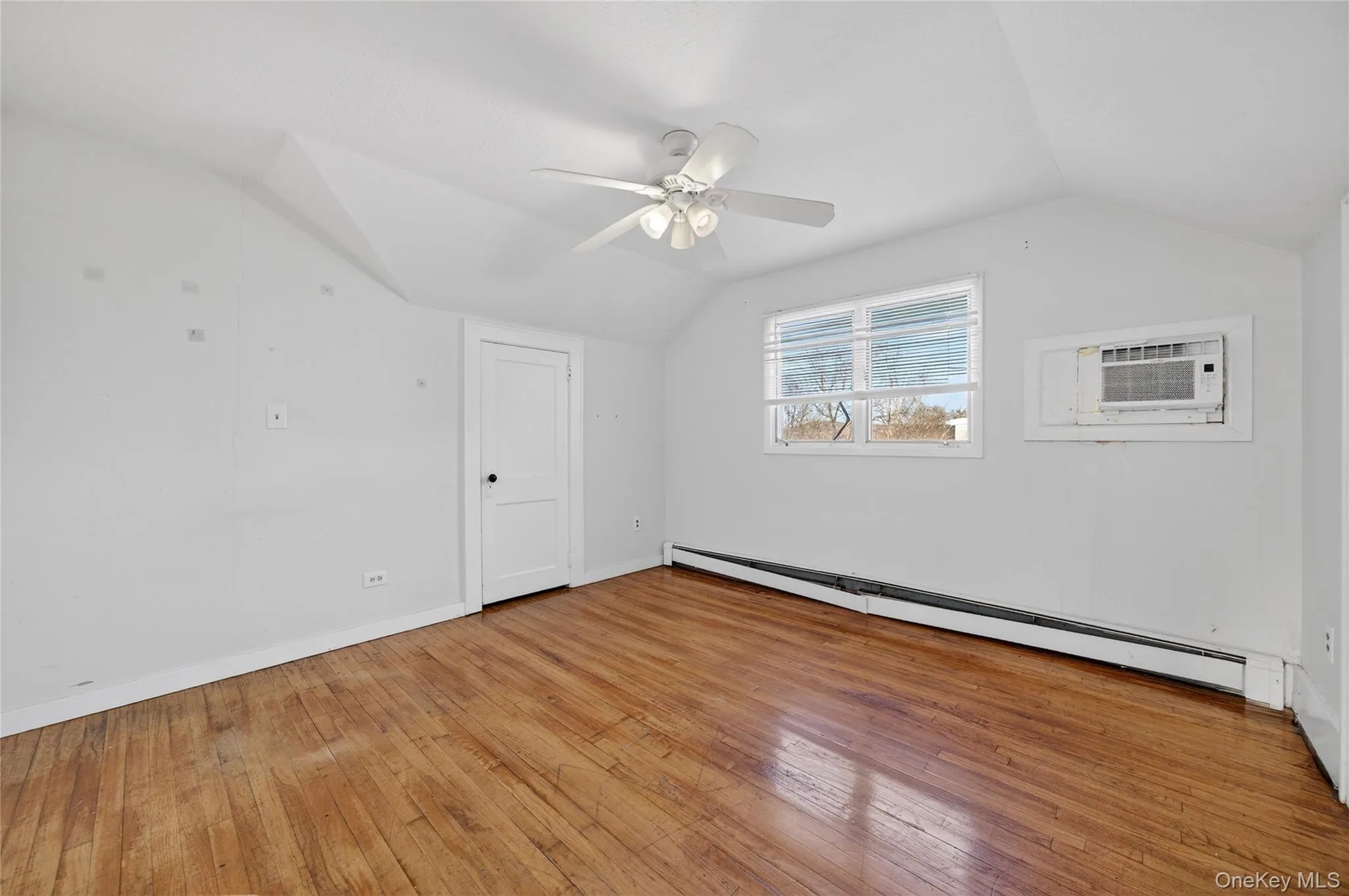 Bonus room with baseboard heating, vaulted ceiling, light wood-style floors, ceiling fan, and a wall unit AC Bonus room with baseboard heating, vaulted ceiling, light wood-style floors, ceiling fan, and a wall unit AC