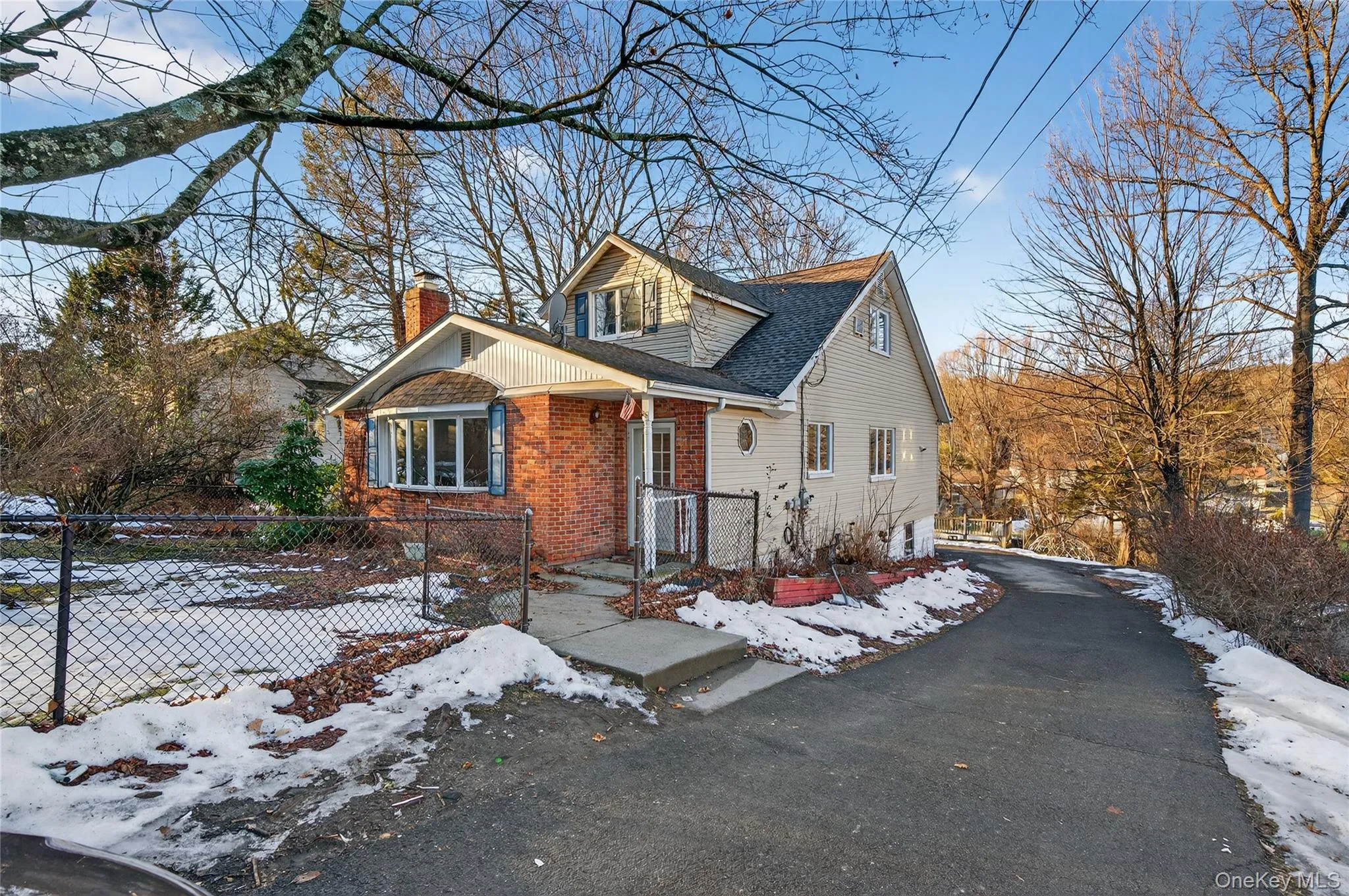 View of front of property with a chimney, brick siding, roof with shingles, a fenced front yard, and a gate View of front of property with a chimney, brick siding, roof with shingles, a fenced front yard, and a gate