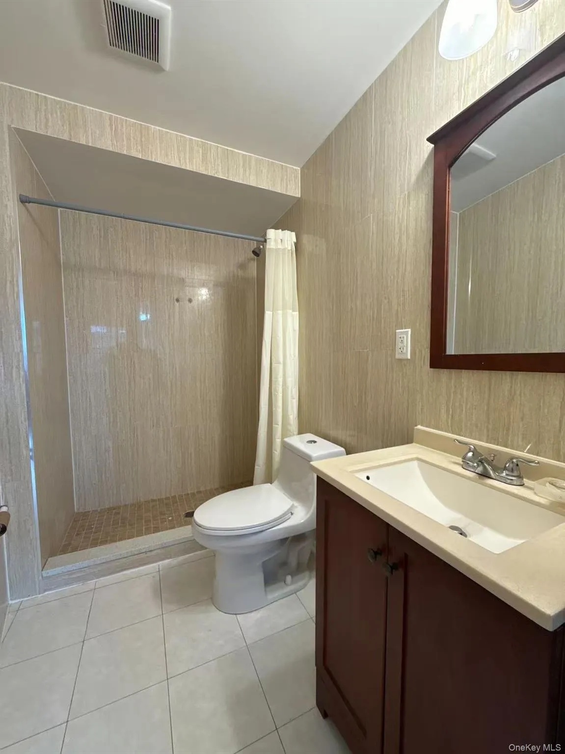 Bathroom featuring vanity, a tile shower, and light tile patterned floors Bathroom featuring vanity, a tile shower, and light tile patterned floors