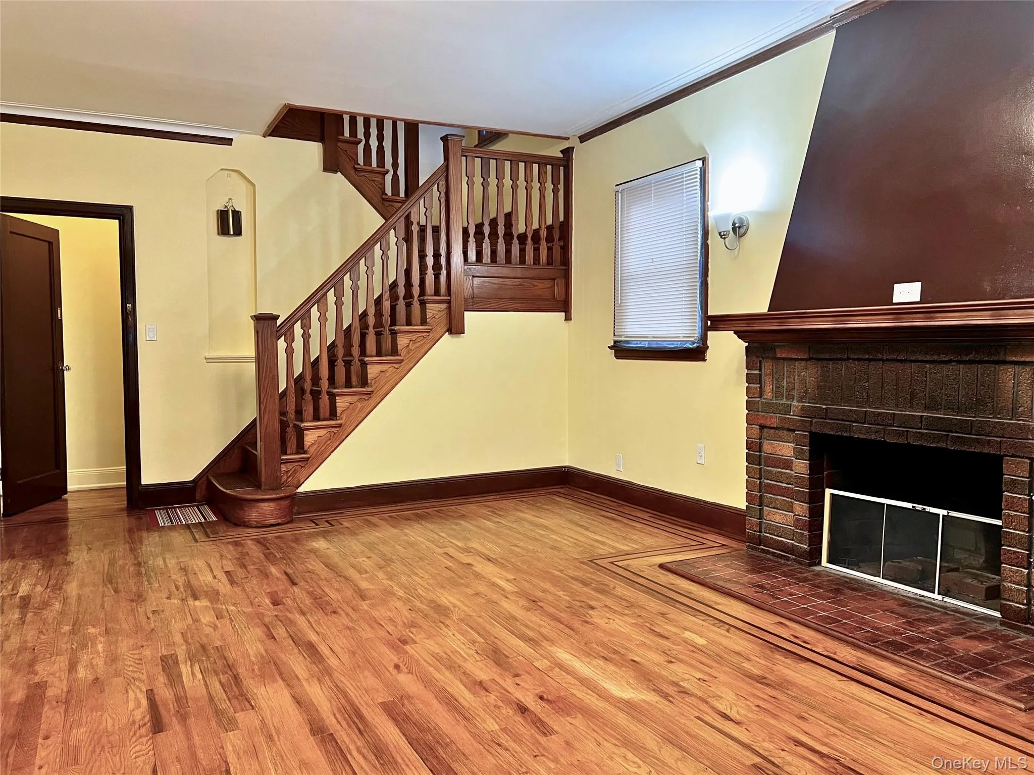 Unfurnished living room featuring ornamental molding, wood finished floors, a fireplace, and stairway Unfurnished living room featuring ornamental molding, wood finished floors, a fireplace, and stairway