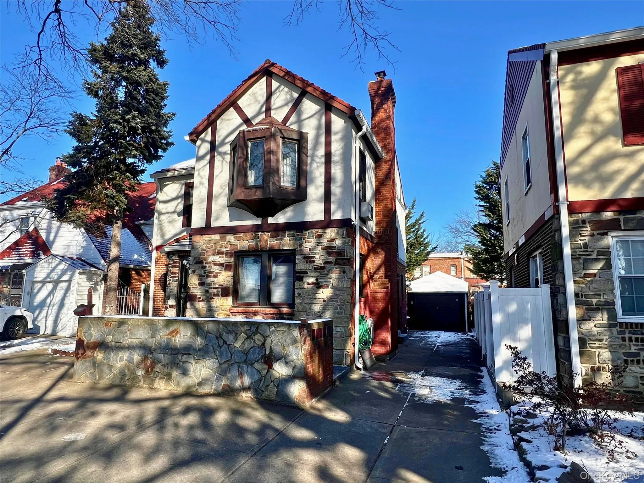 View of front of property featuring stone siding, a chimney, and a garage View of front of property featuring stone siding, a chimney, and a garage