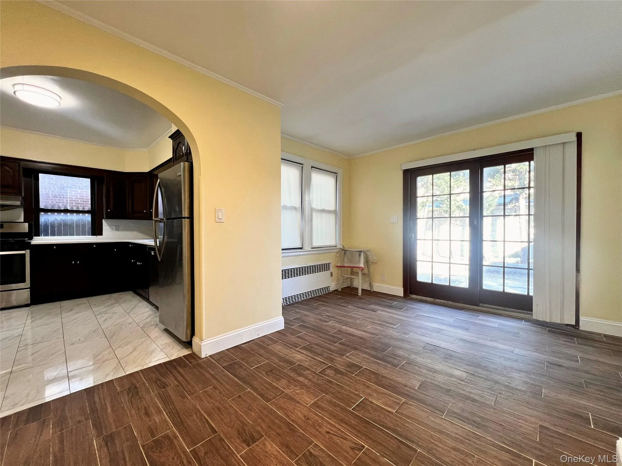 Kitchen with stainless steel appliances, healthy amount of natural light, radiator heating unit, light countertops, and ornamental molding Kitchen with stainless steel appliances, healthy amount of natural light, radiator heating unit, light countertops, and ornamental molding