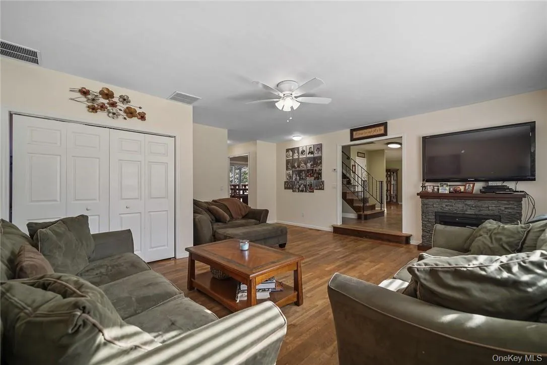 Living area with a fireplace, stairs, dark wood finished floors, and ceiling fan Living area with a fireplace, stairs, dark wood finished floors, and ceiling fan