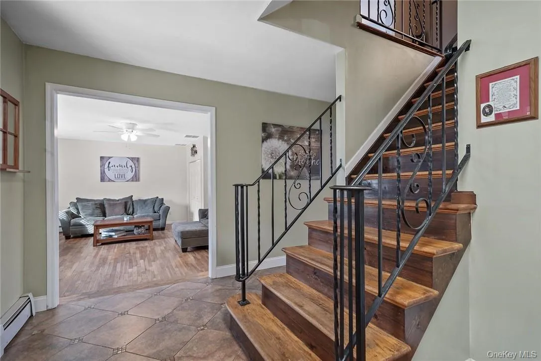 Stairway with a baseboard heating unit, tile patterned floors, and a ceiling fan Stairway with a baseboard heating unit, tile patterned floors, and a ceiling fan