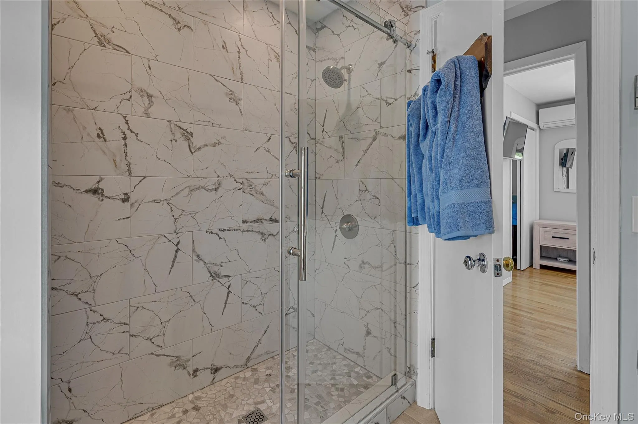 Full bathroom with a marble finish shower and wood finished floors Full bathroom with a marble finish shower and wood finished floors