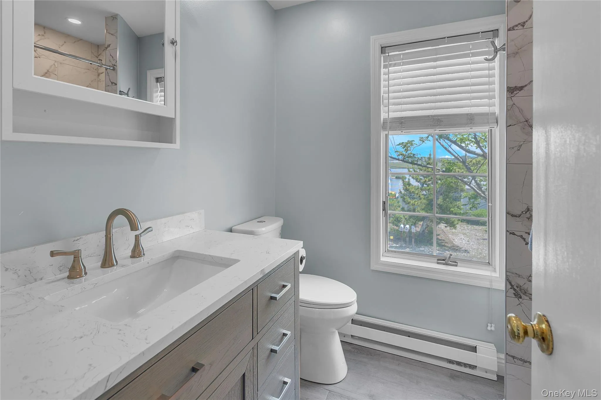 Bathroom featuring a baseboard radiator, vanity, and a marble finish shower Bathroom featuring a baseboard radiator, vanity, and a marble finish shower
