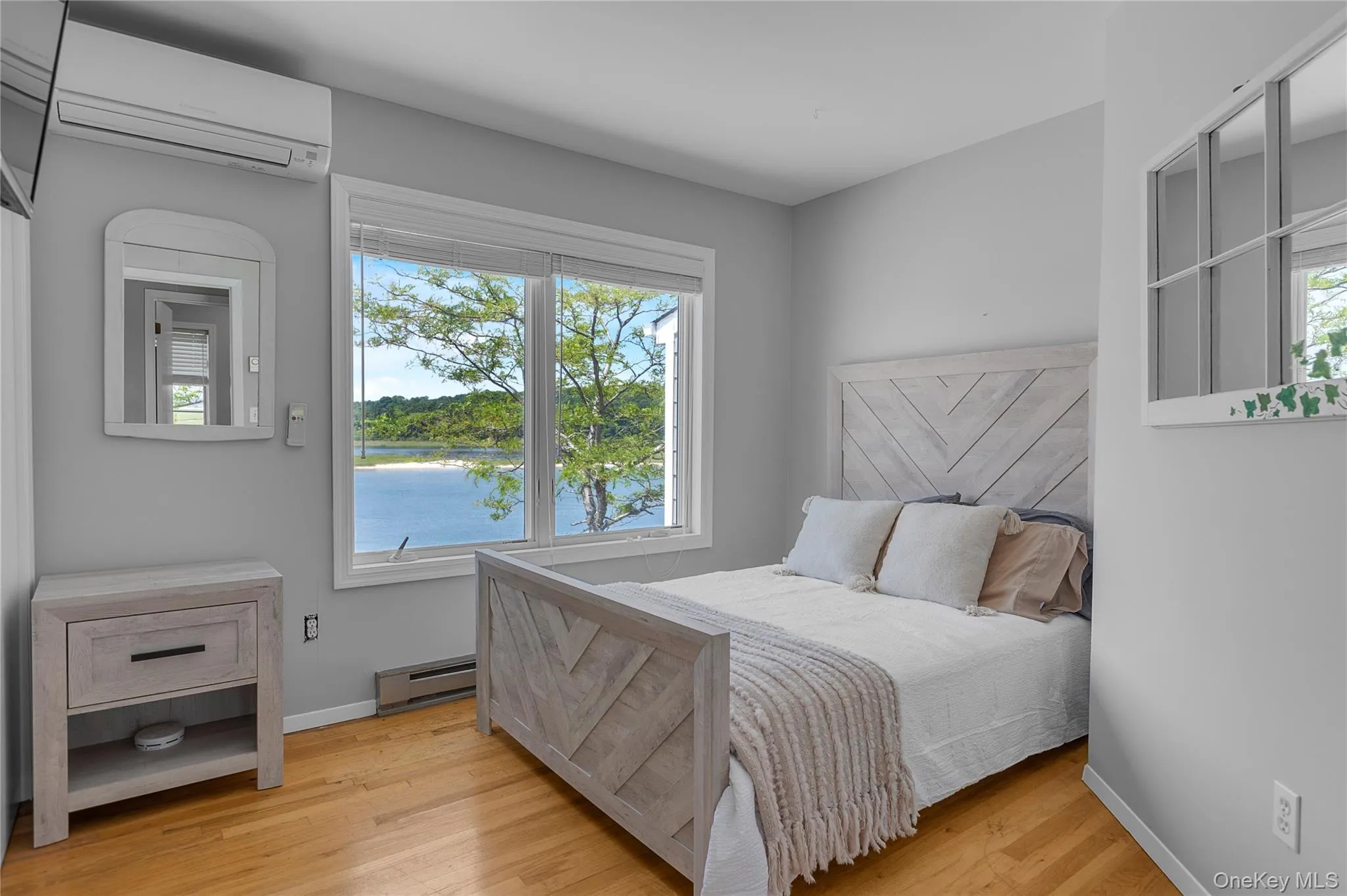 Bedroom featuring a wall unit AC, multiple windows, and baseboard heating Bedroom featuring a wall unit AC, multiple windows, and baseboard heating