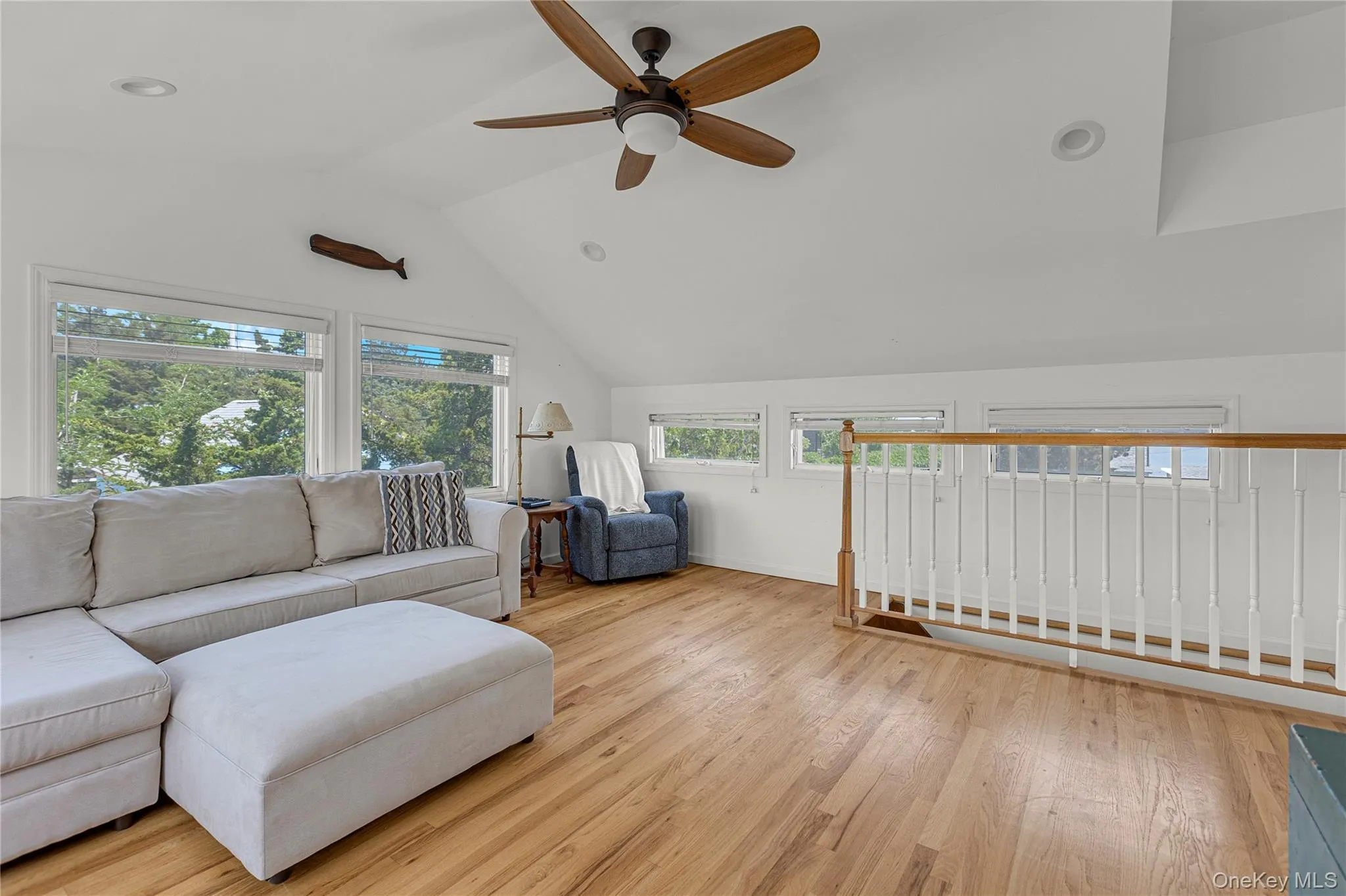 Living room with ceiling fan, vaulted ceiling, and light wood-style floors Living room with ceiling fan, vaulted ceiling, and light wood-style floors
