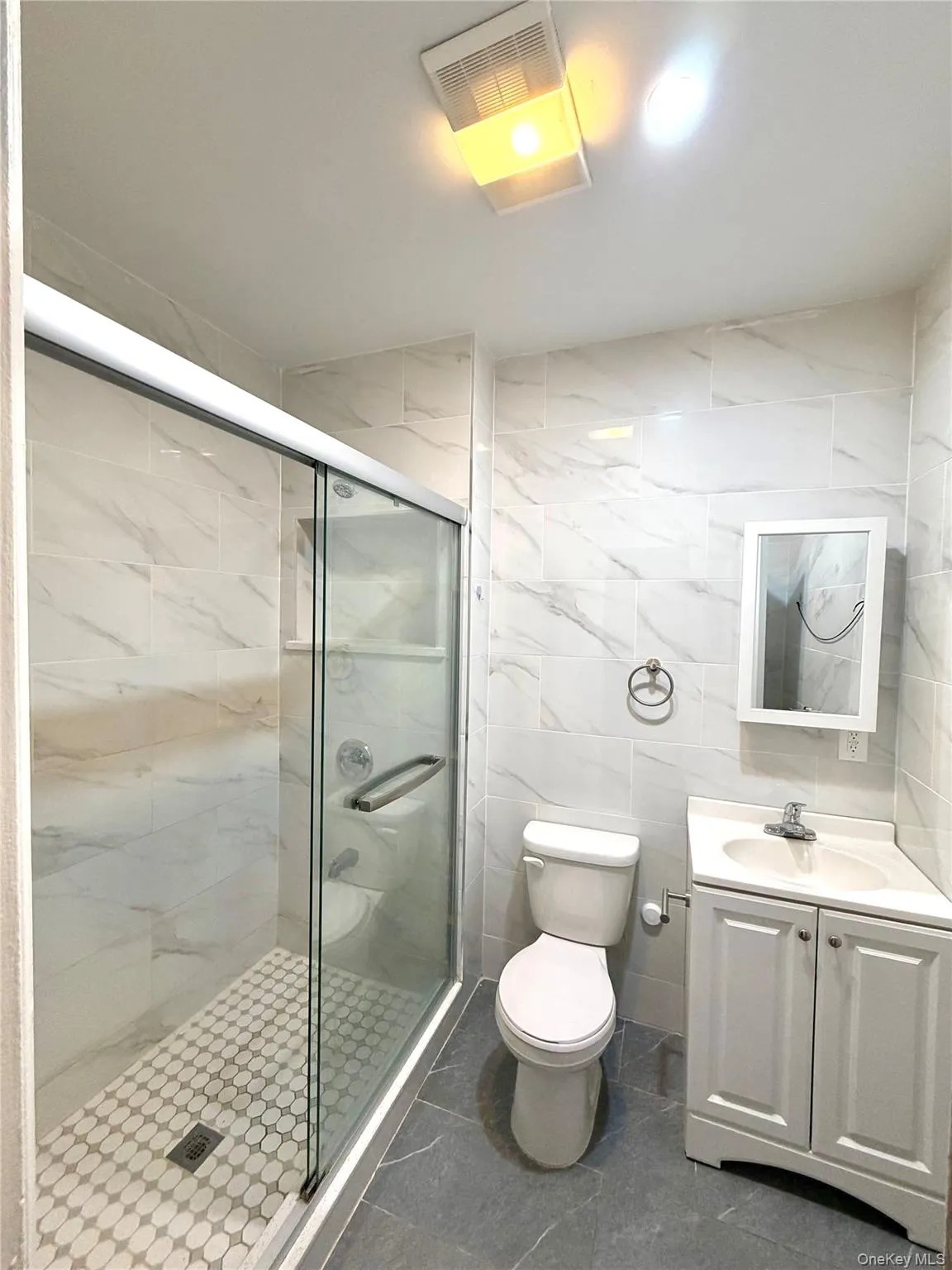 Bathroom with tile walls, vanity, and a shower stall Bathroom with tile walls, vanity, and a shower stall