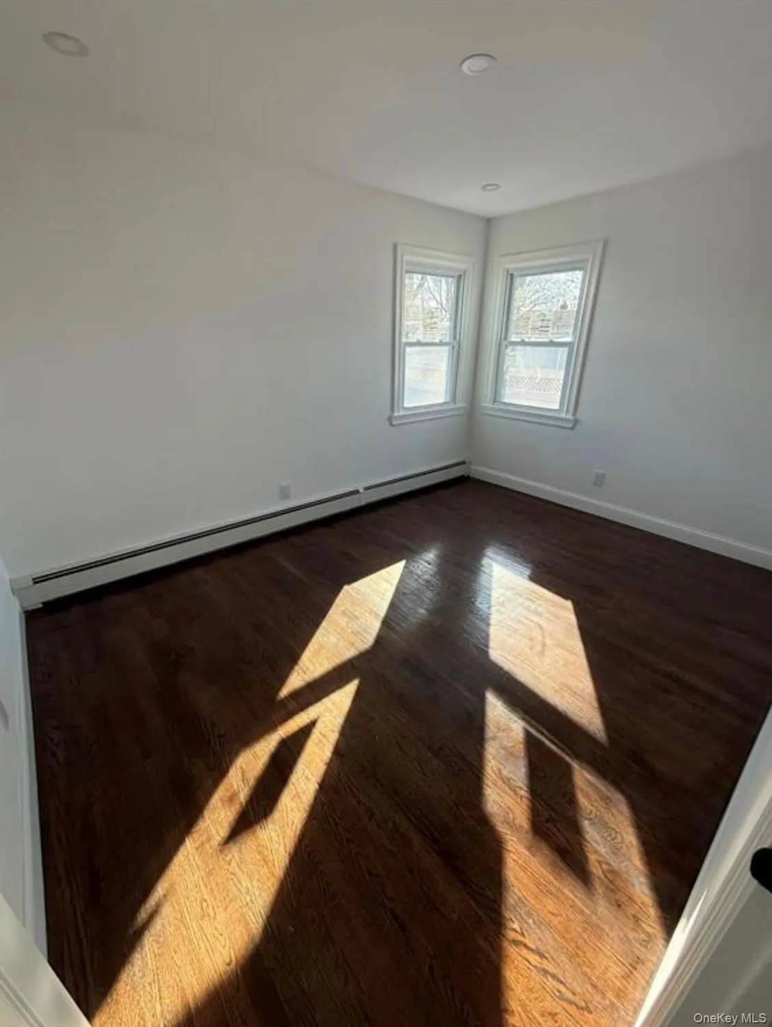 Spare room featuring dark wood-style flooring, a baseboard radiator, baseboards, and recessed lighting Spare room featuring dark wood-style flooring, a baseboard radiator, baseboards, and recessed lighting