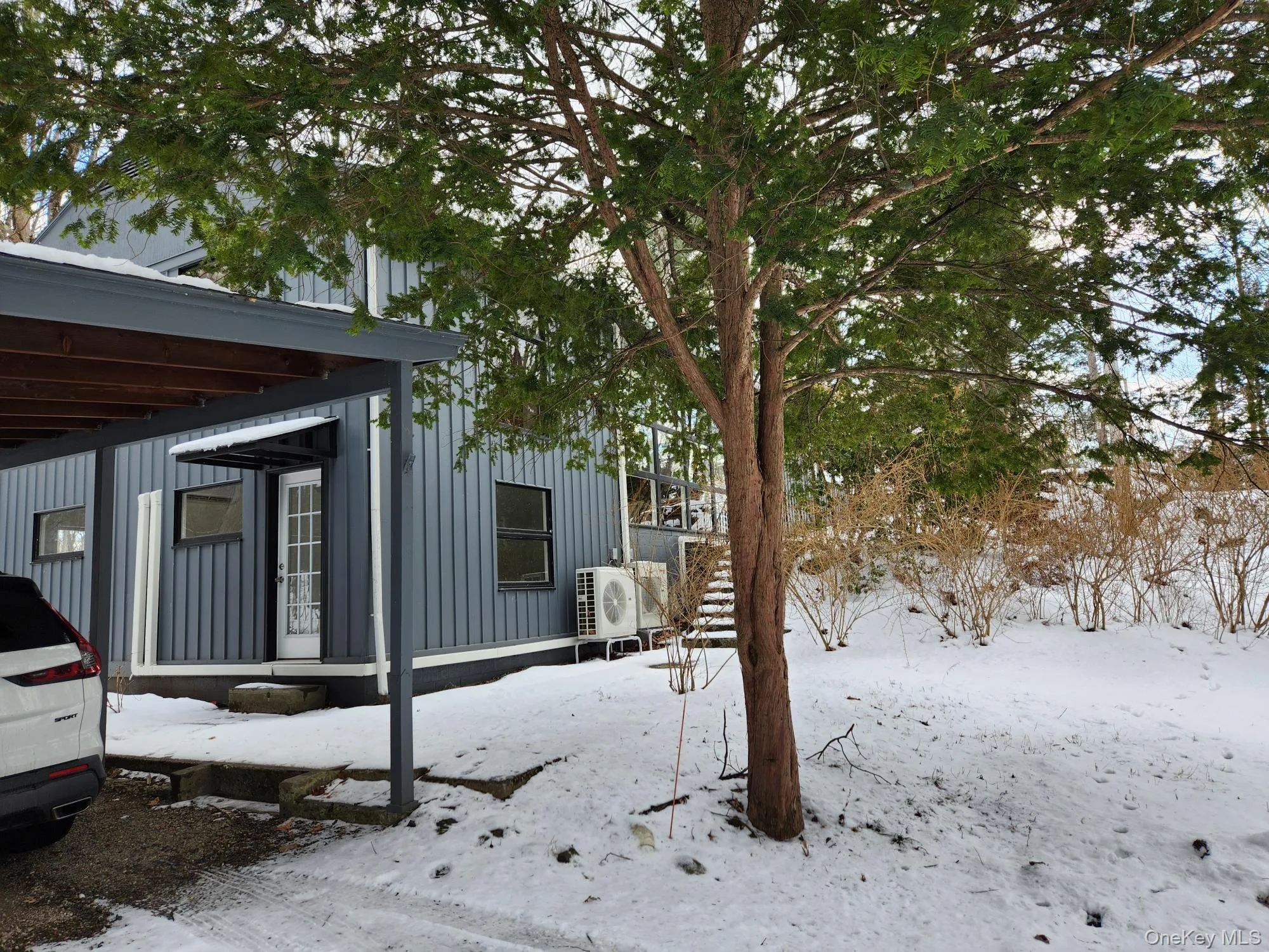 View of snow covered exterior with board and batten siding and stairway View of snow covered exterior with board and batten siding and stairway
