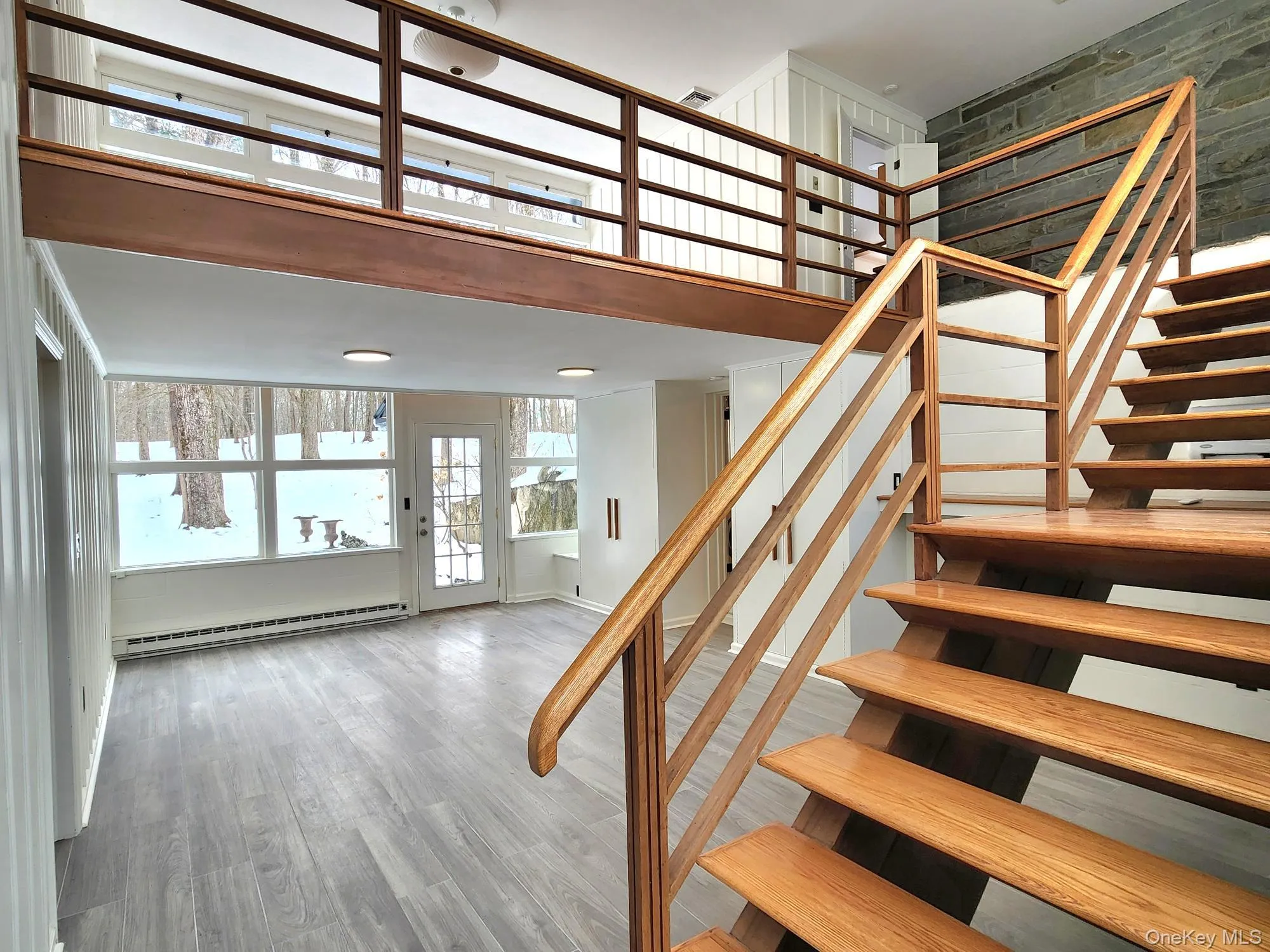 Stairway with wood finished floors, a baseboard heating unit, and a towering ceiling Stairway with wood finished floors, a baseboard heating unit, and a towering ceiling