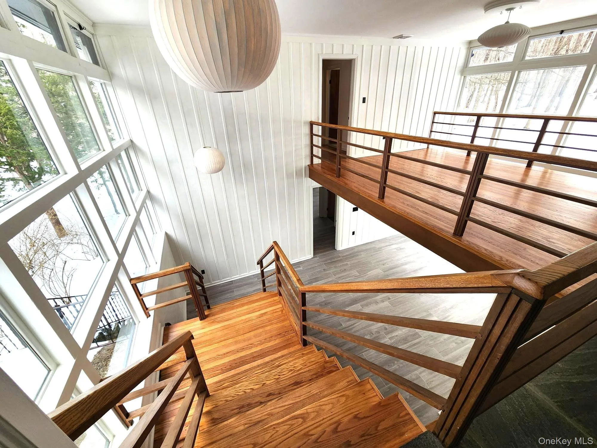 Staircase featuring plenty of natural light, wood finished floors, and wood walls Staircase featuring plenty of natural light, wood finished floors, and wood walls