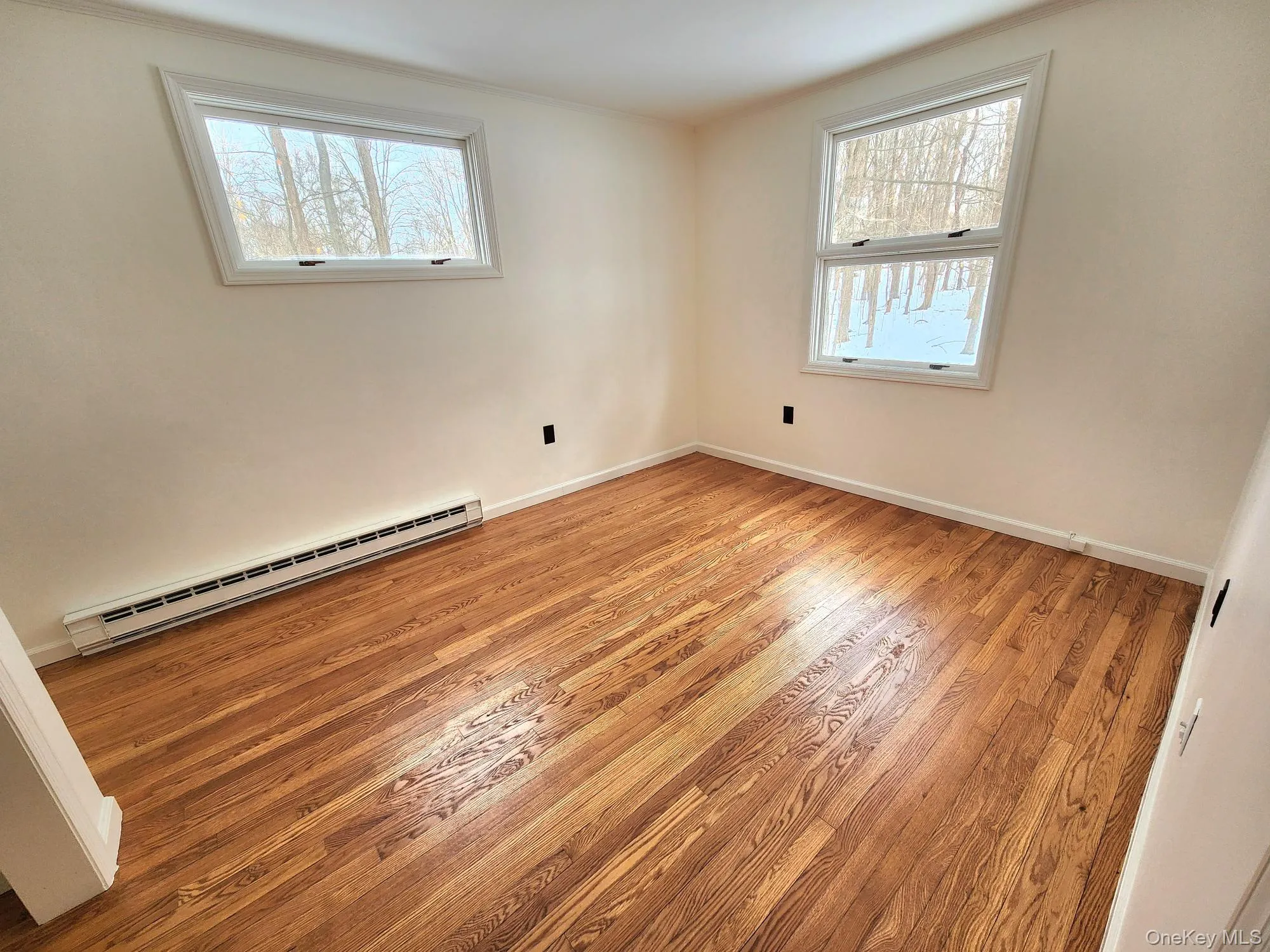 Empty room with light wood-style floors and baseboard heating Empty room with light wood-style floors and baseboard heating
