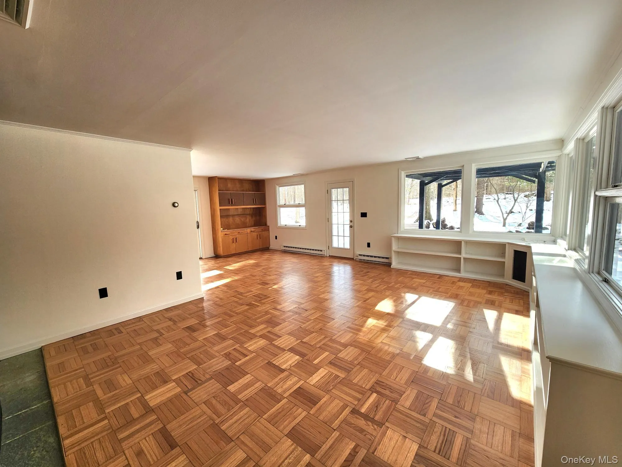 Unfurnished living room with baseboard heating, a baseboard heating unit, and parquet flooring Unfurnished living room with baseboard heating, a baseboard heating unit, and parquet flooring