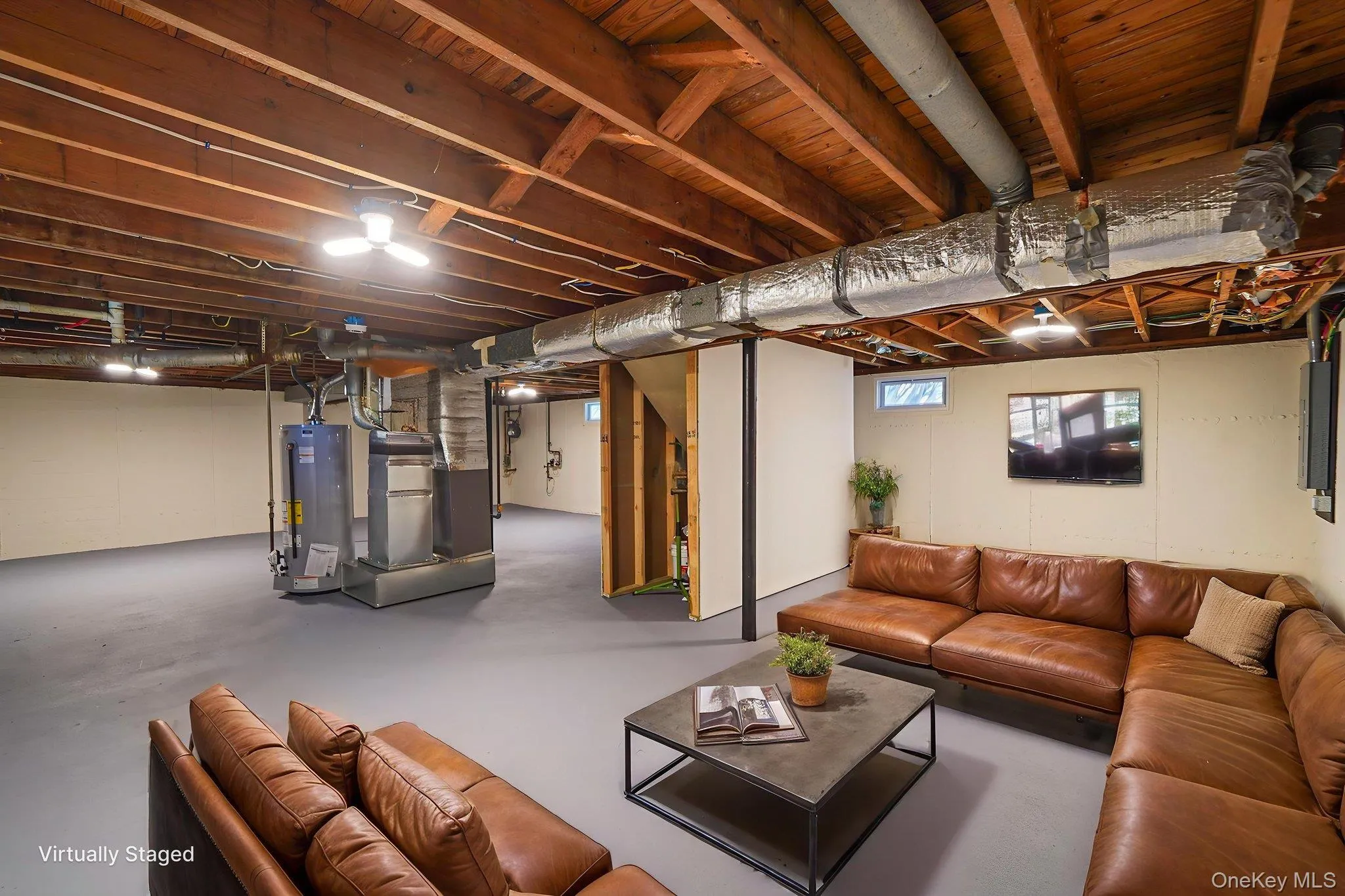 Spacious lower-level area with exposed ceiling joists and ductwork, painted walls, ceiling-mounted lighting, and a small transom window Spacious lower-level area with exposed ceiling joists and ductwork, painted walls, ceiling-mounted lighting, and a small transom window