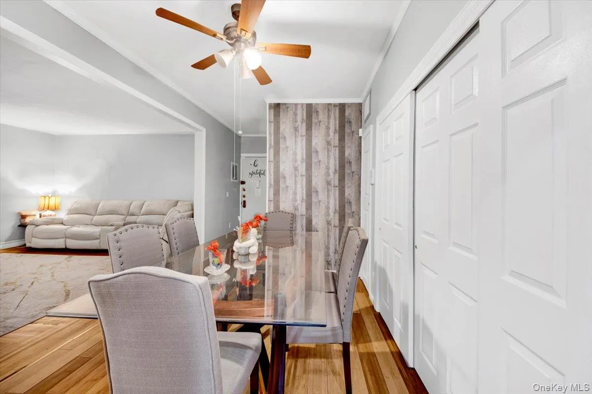 Dining space featuring wood finished floors, ornamental molding, and a ceiling fan Dining space featuring wood finished floors, ornamental molding, and a ceiling fan