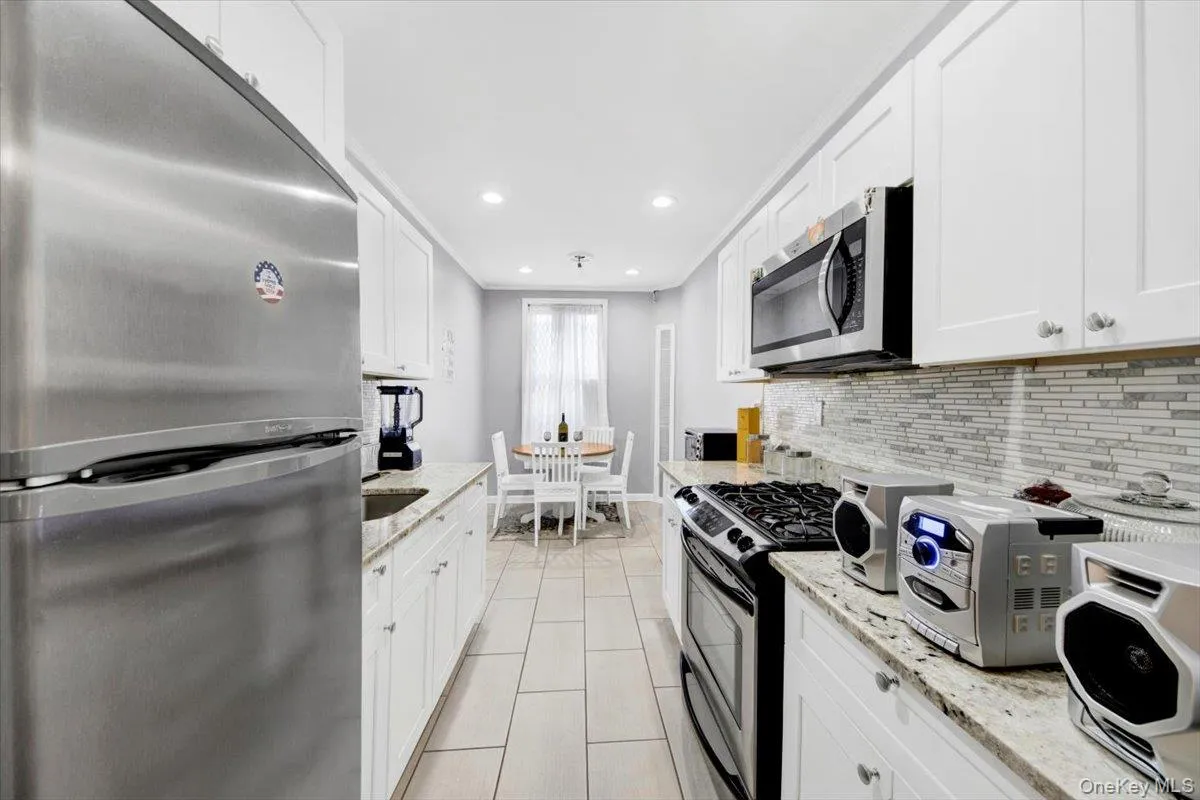 Kitchen with stainless steel appliances, white cabinetry, light stone counters, recessed lighting, and light tile patterned floors Kitchen with stainless steel appliances, white cabinetry, light stone counters, recessed lighting, and light tile patterned floors