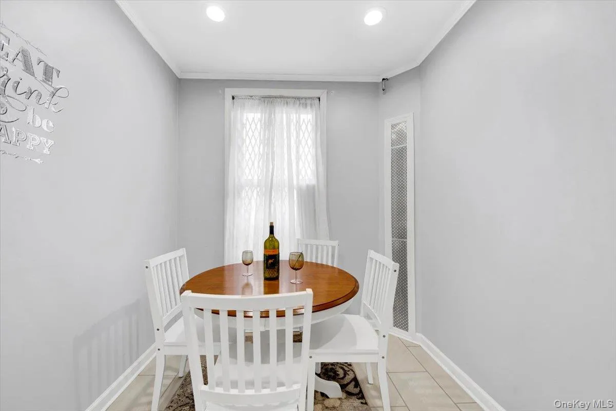 Dining room featuring ornamental molding, light tile patterned floors, recessed lighting, and a heating unit Dining room featuring ornamental molding, light tile patterned floors, recessed lighting, and a heating unit