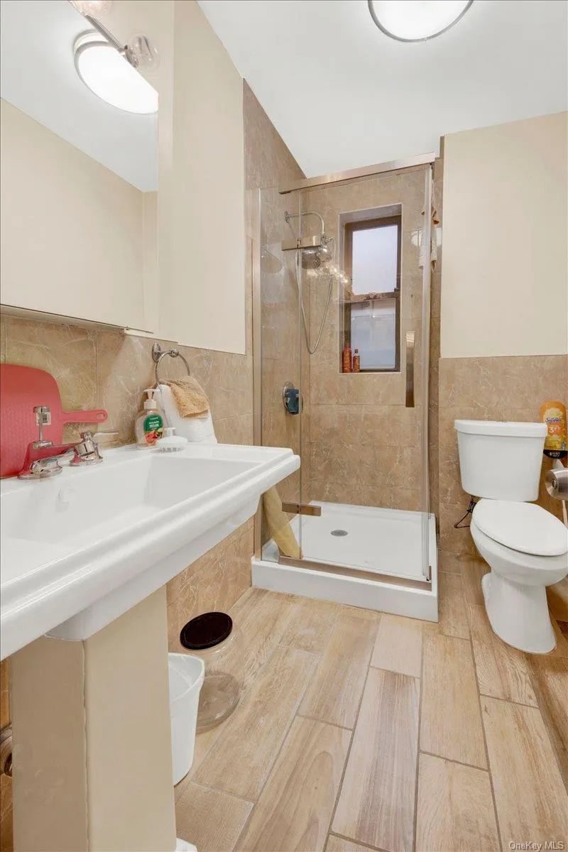 Bathroom featuring tile walls, a stall shower, and a wainscoted wall Bathroom featuring tile walls, a stall shower, and a wainscoted wall