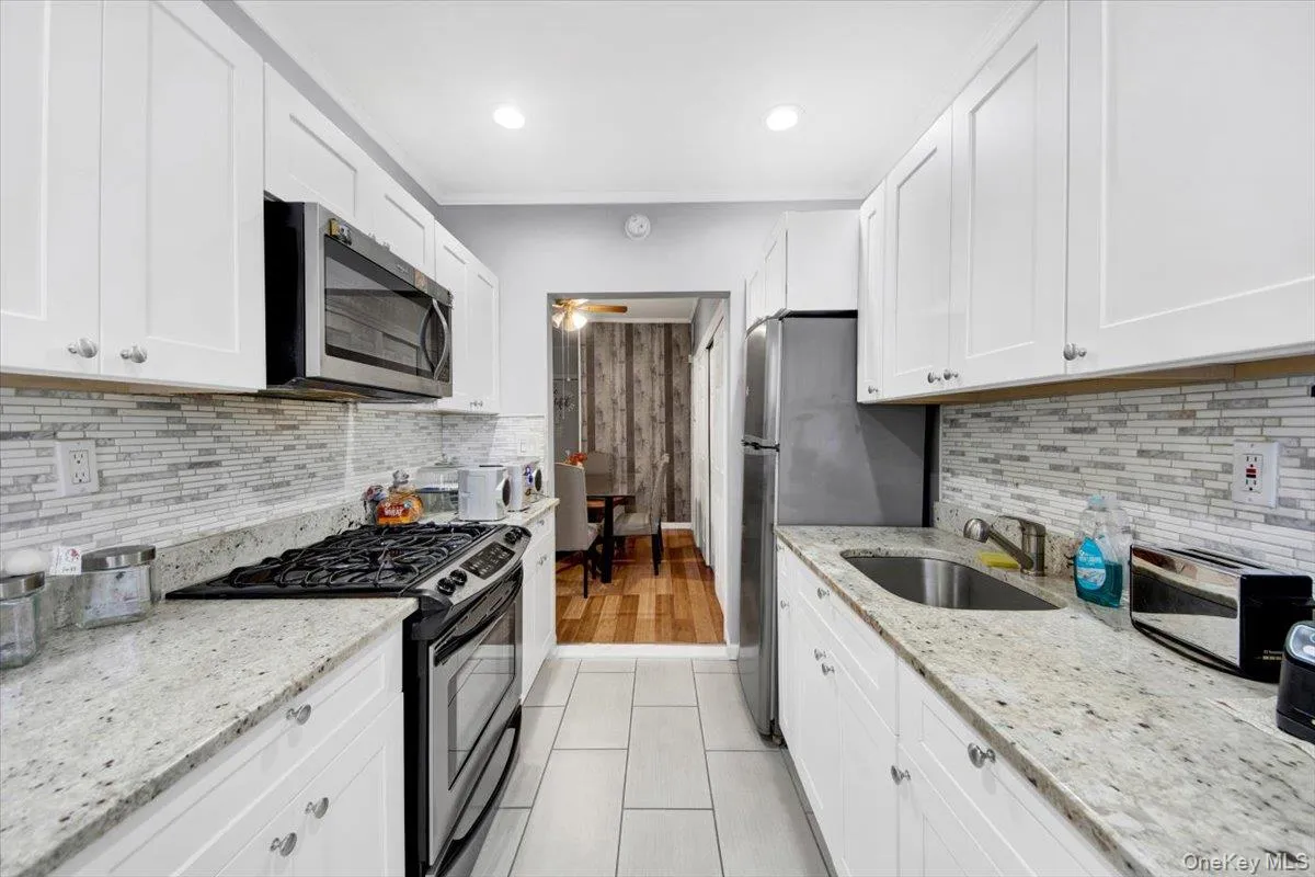 Kitchen featuring stainless steel appliances, light stone countertops, white cabinets, ceiling fan, and recessed lighting Kitchen featuring stainless steel appliances, light stone countertops, white cabinets, ceiling fan, and recessed lighting
