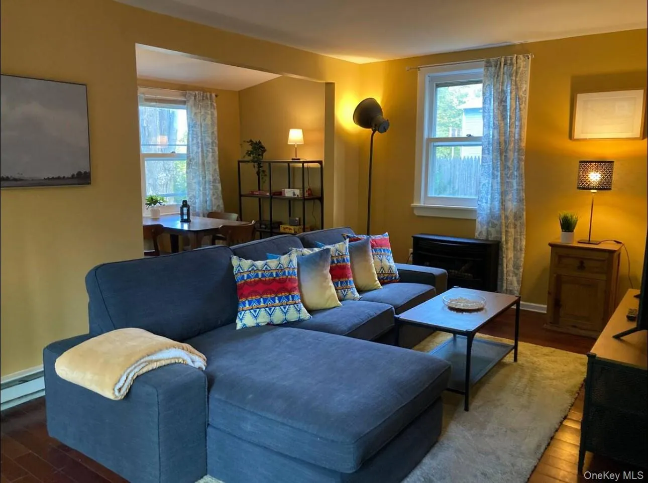 Living room with wood finished floors and baseboard heating Living room with wood finished floors and baseboard heating