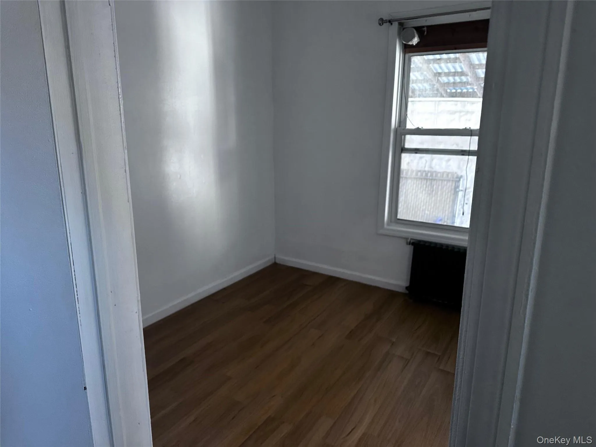 Unfurnished room with radiator heating unit and dark wood-type flooring Unfurnished room with radiator heating unit and dark wood-type flooring