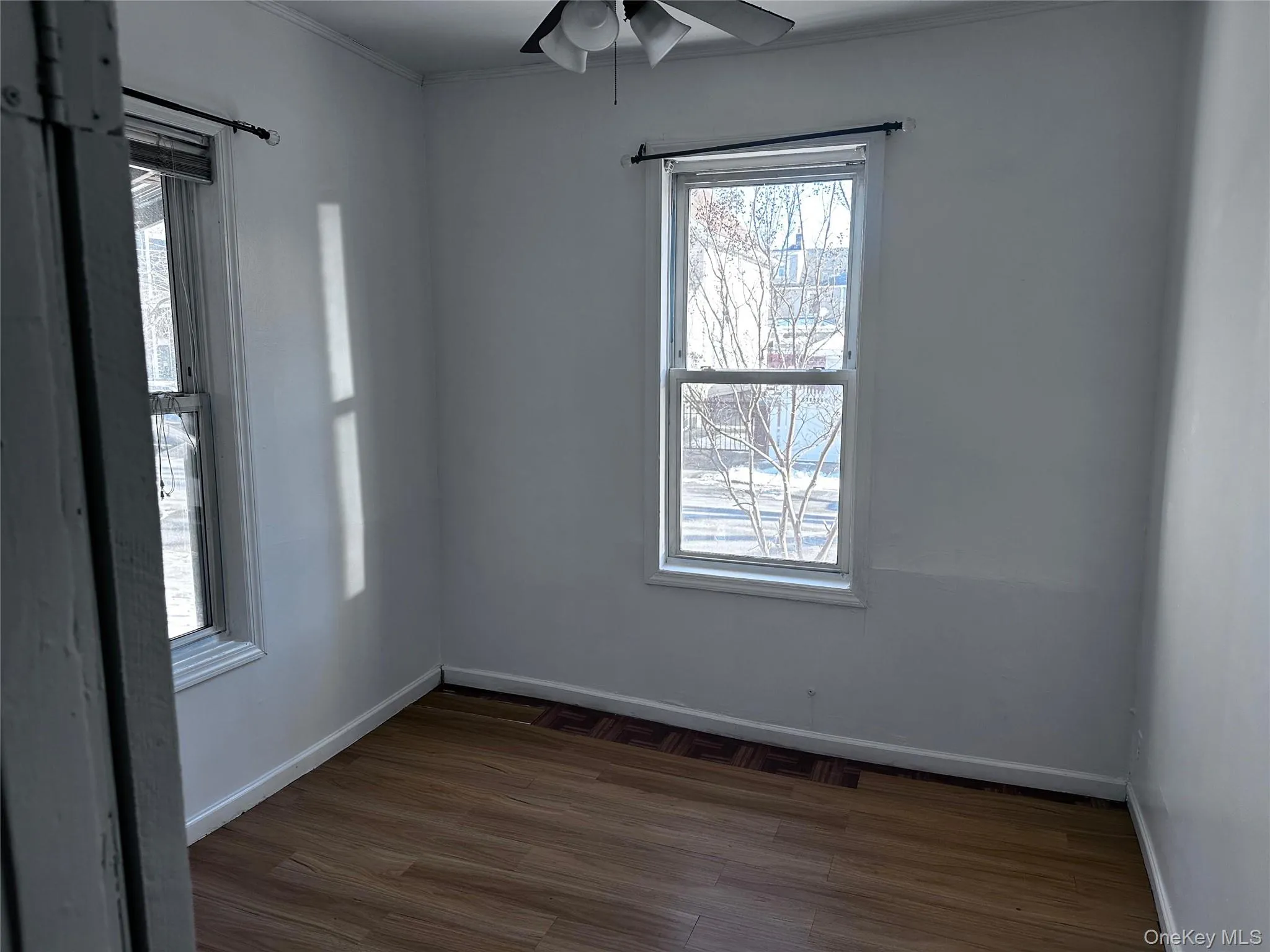 Unfurnished room featuring dark wood-style floors, ceiling fan, and crown molding Unfurnished room featuring dark wood-style floors, ceiling fan, and crown molding