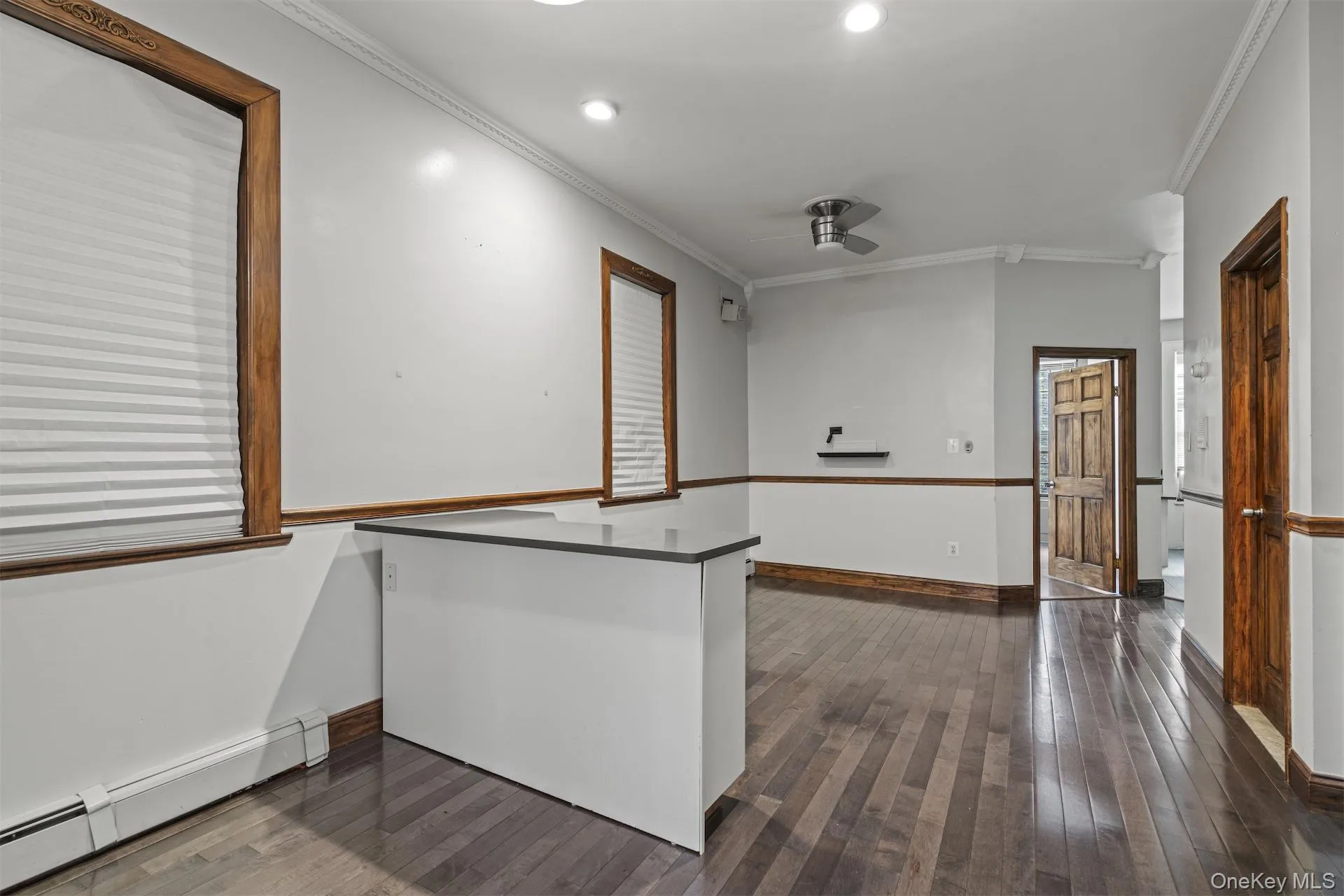 Spare room with a baseboard heating unit, ornamental molding, dark wood-style flooring, and ceiling fan Spare room with a baseboard heating unit, ornamental molding, dark wood-style flooring, and ceiling fan