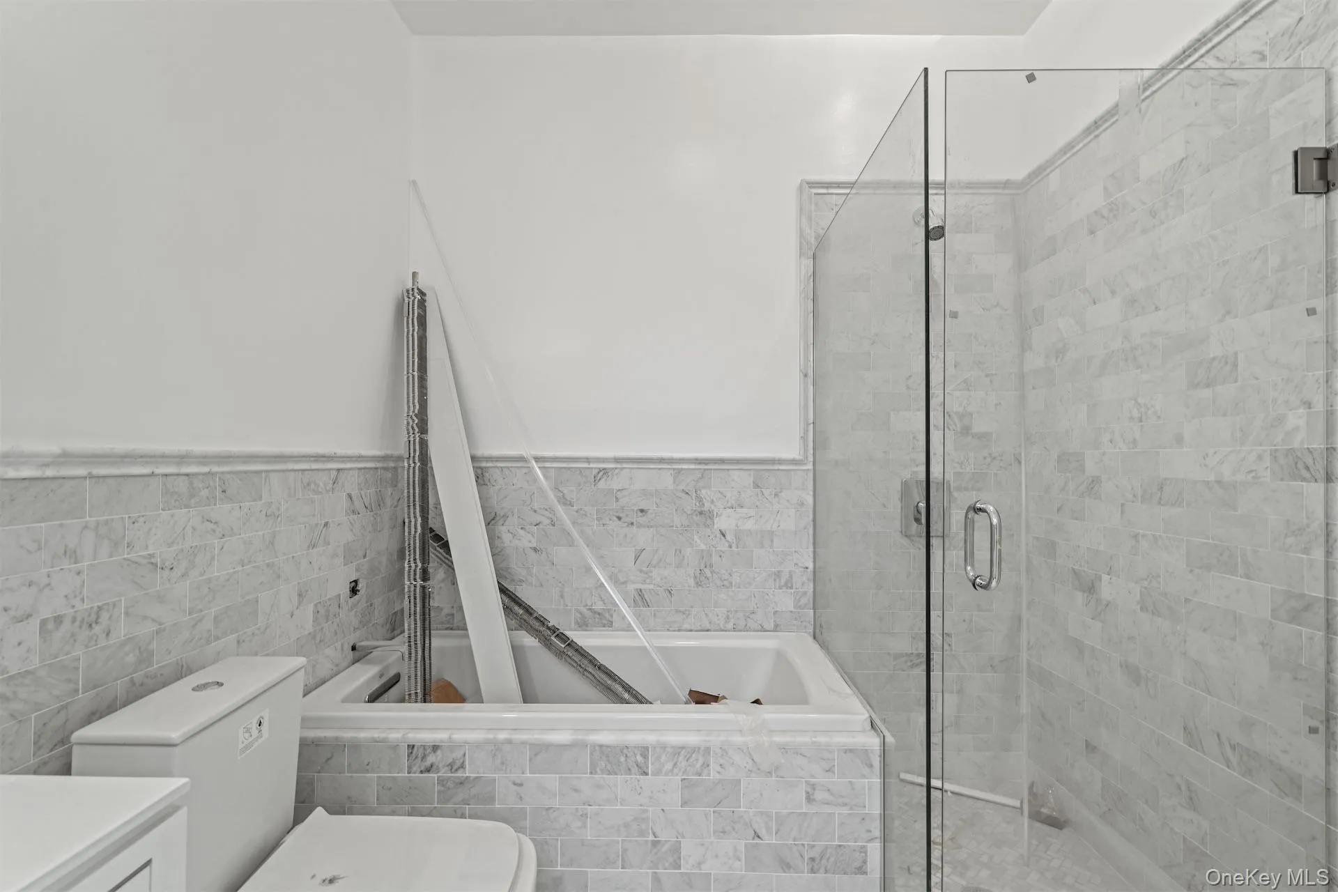 Bathroom featuring a bath, a shower stall, vanity, tile walls, and a wainscoted wall Bathroom featuring a bath, a shower stall, vanity, tile walls, and a wainscoted wall