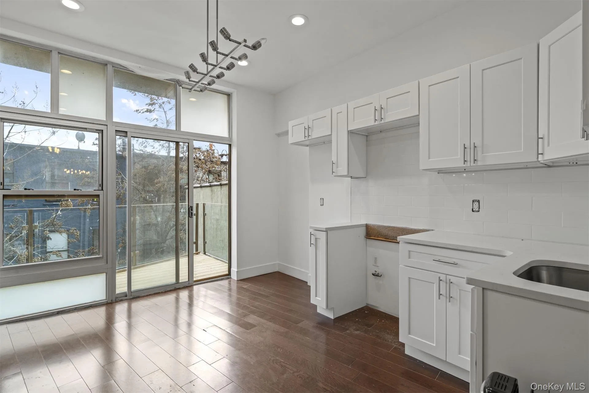 Kitchen with white cabinetry, hanging light fixtures, dark wood finished floors, light stone counters, and recessed lighting Kitchen with white cabinetry, hanging light fixtures, dark wood finished floors, light stone counters, and recessed lighting