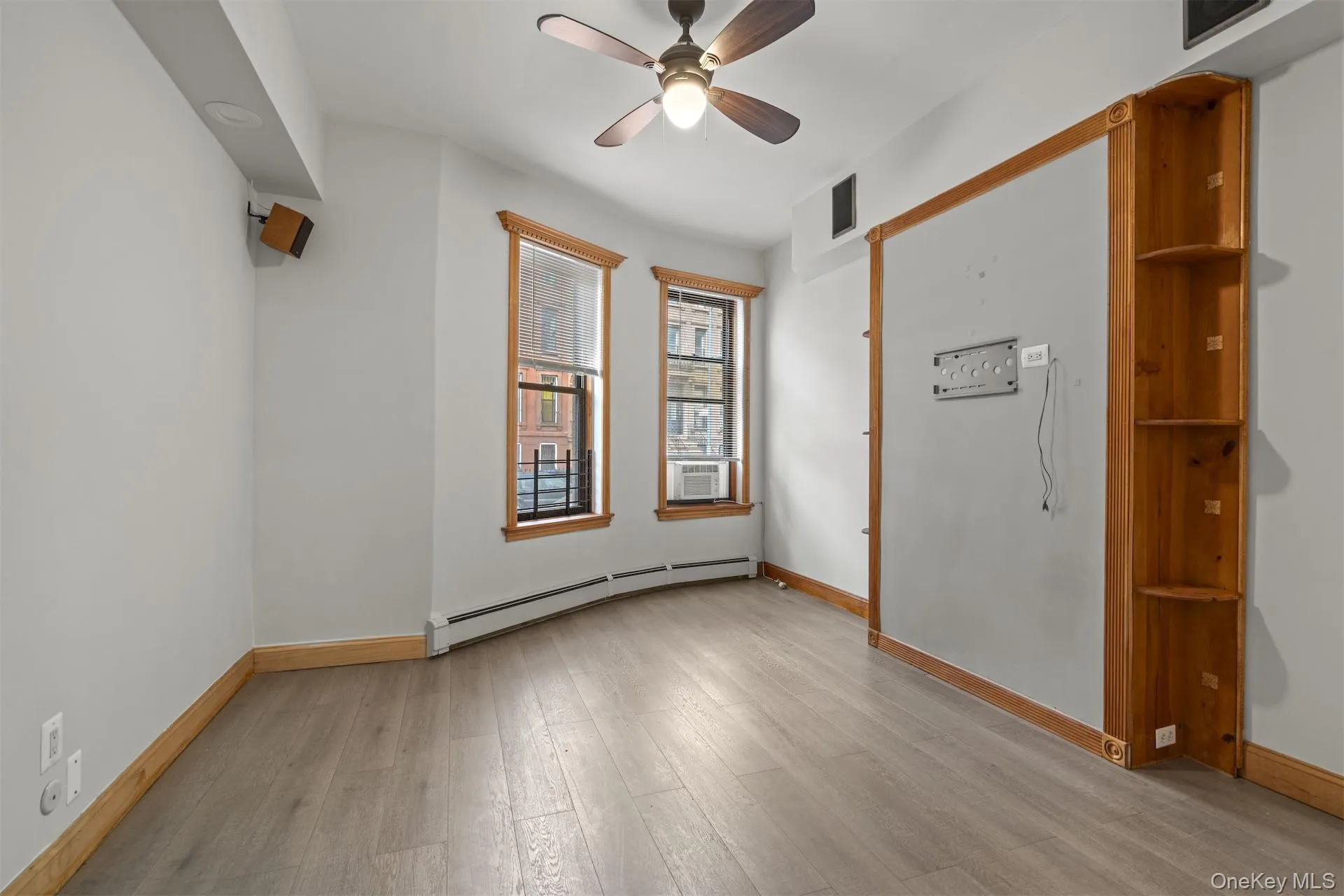 Unfurnished room featuring baseboard heating, ceiling fan, and light wood finished floors Unfurnished room featuring baseboard heating, ceiling fan, and light wood finished floors