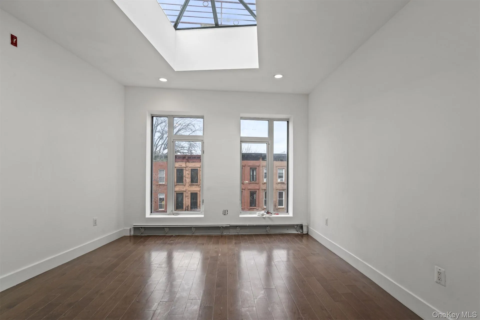 Empty room with a skylight, dark wood-style floors, and recessed lighting Empty room with a skylight, dark wood-style floors, and recessed lighting