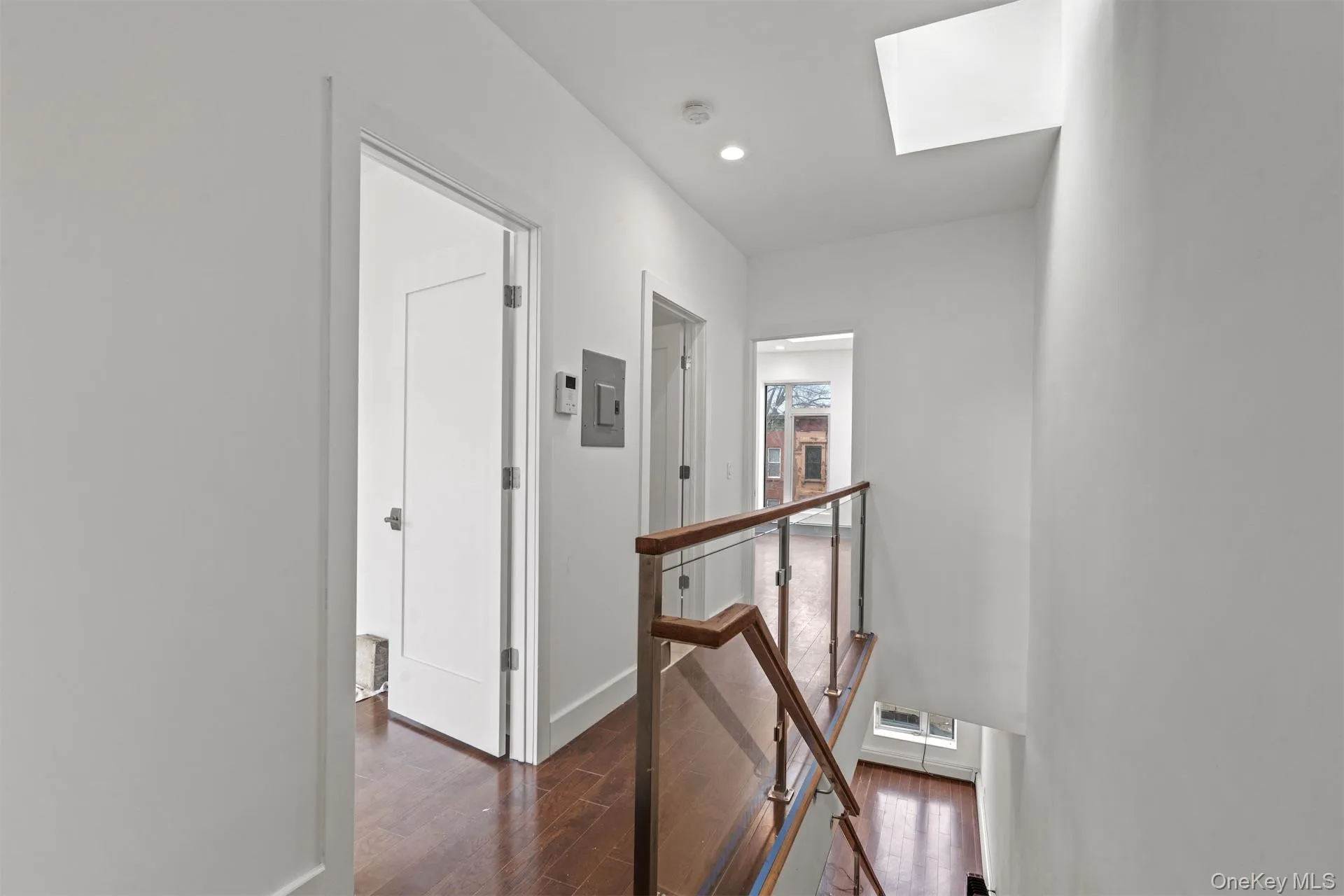 Hallway featuring an upstairs landing, a skylight, dark wood finished floors, and recessed lighting Hallway featuring an upstairs landing, a skylight, dark wood finished floors, and recessed lighting