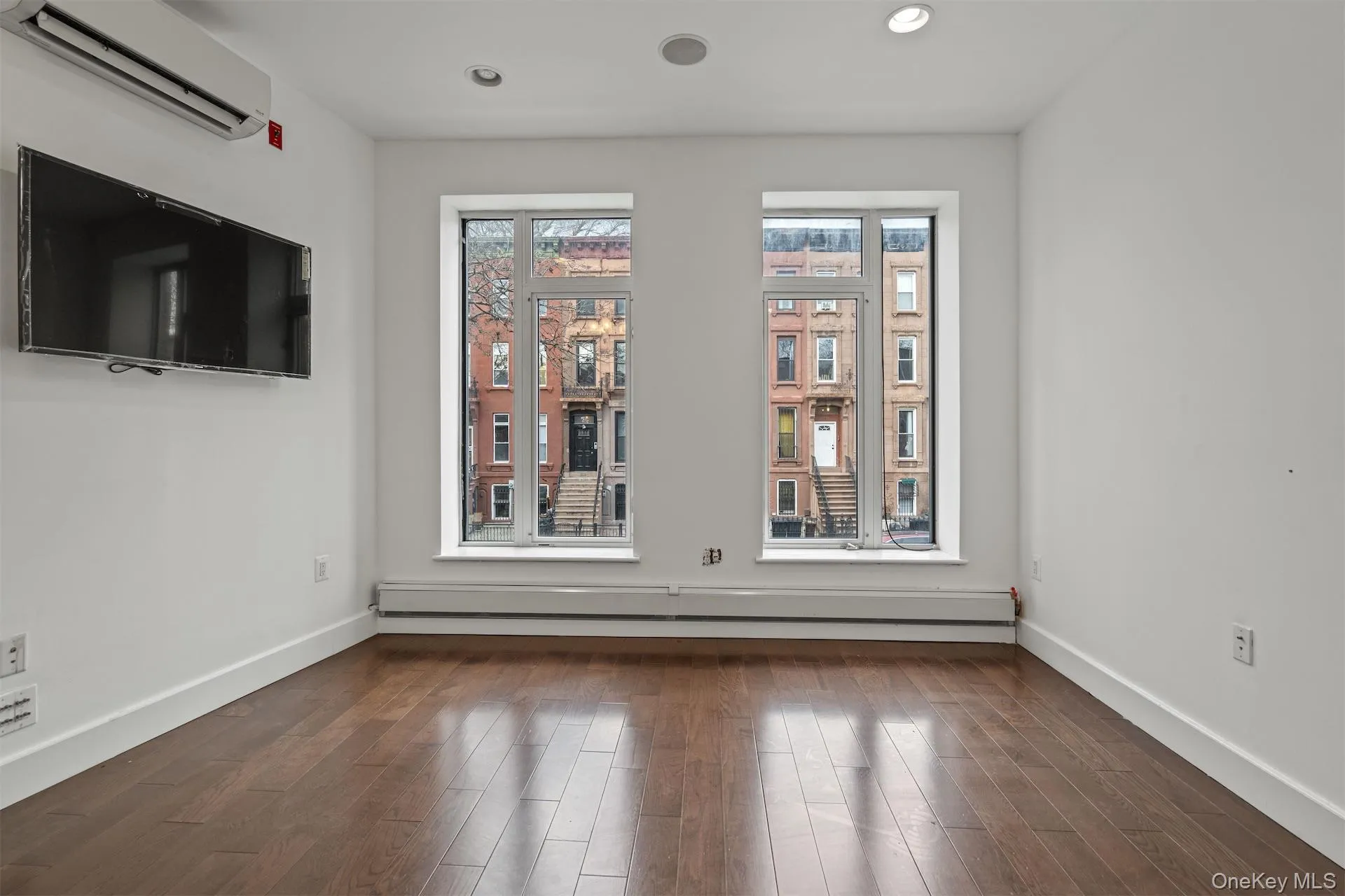 Spare room featuring an AC wall unit, baseboard heating, dark wood-type flooring, and recessed lighting Spare room featuring an AC wall unit, baseboard heating, dark wood-type flooring, and recessed lighting