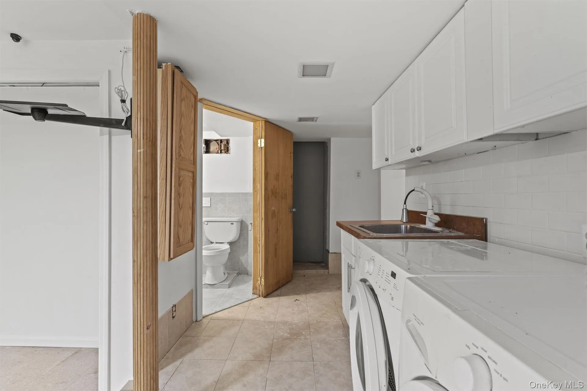 Laundry room featuring cabinet space, washing machine and clothes dryer, and light tile patterned floors Laundry room featuring cabinet space, washing machine and clothes dryer, and light tile patterned floors