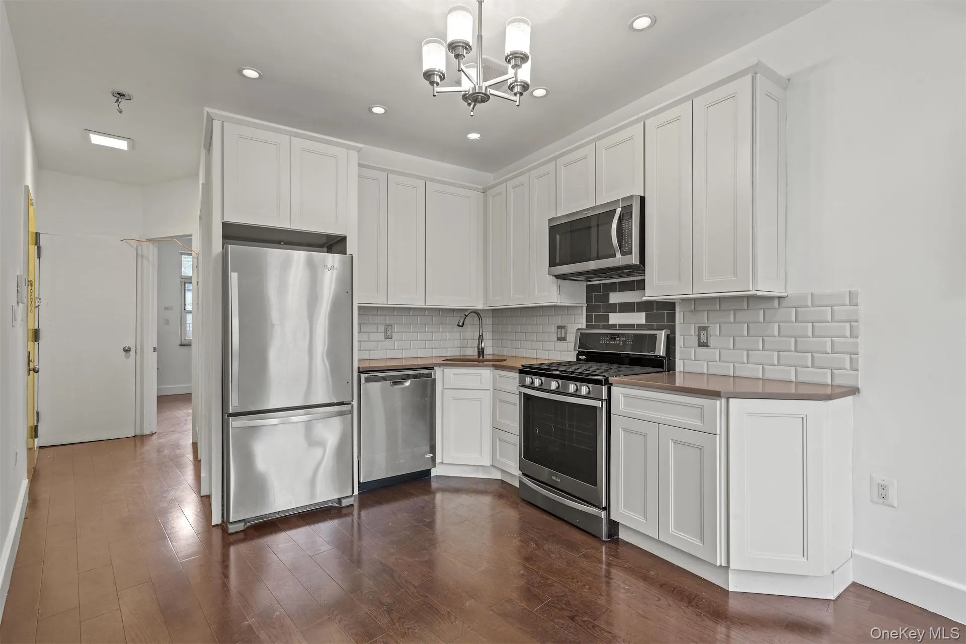 Kitchen with stainless steel appliances, white cabinets, backsplash, a chandelier, and recessed lighting Kitchen with stainless steel appliances, white cabinets, backsplash, a chandelier, and recessed lighting