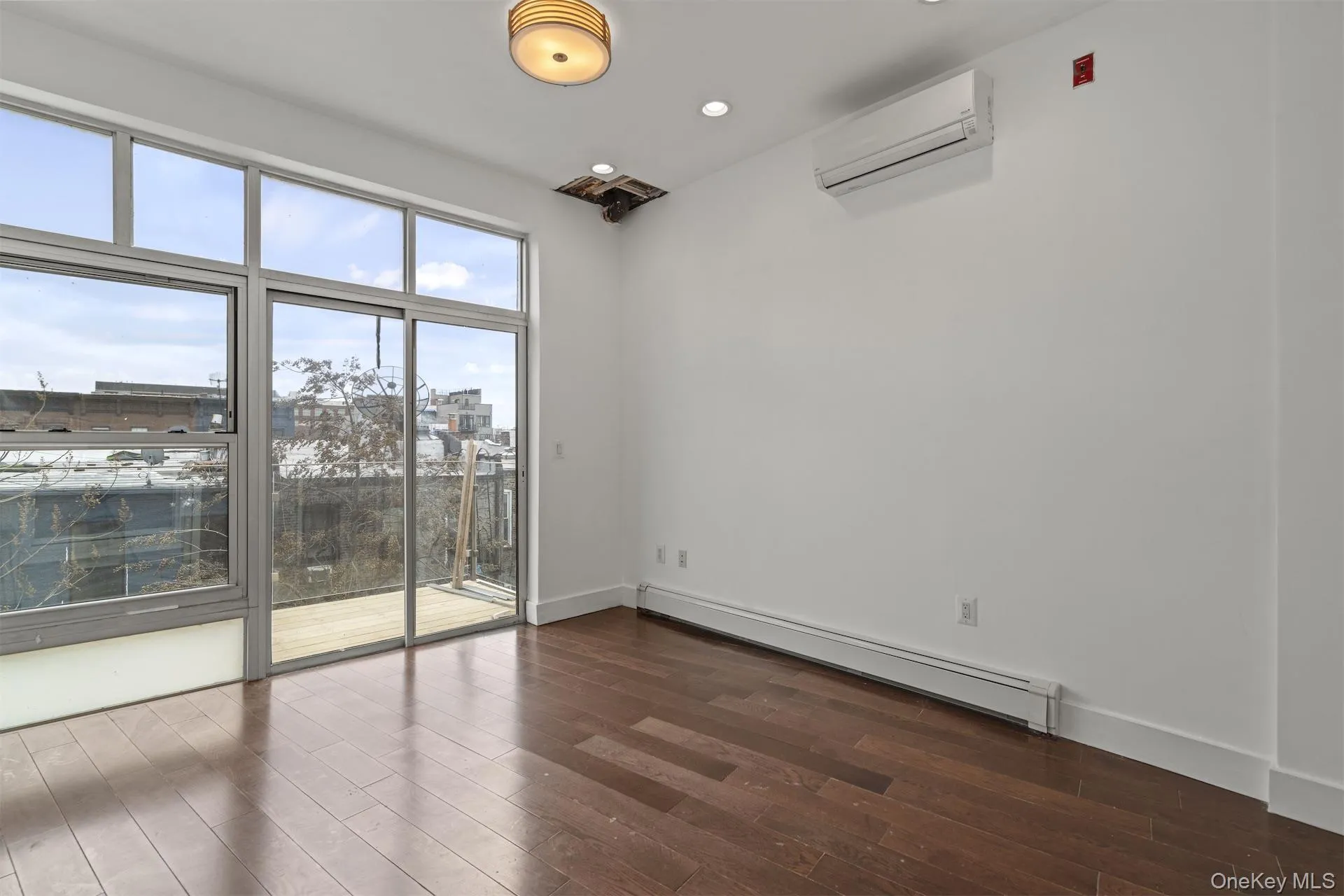 Empty room featuring a baseboard heating unit, dark wood-style floors, an AC wall unit, and recessed lighting Empty room featuring a baseboard heating unit, dark wood-style floors, an AC wall unit, and recessed lighting