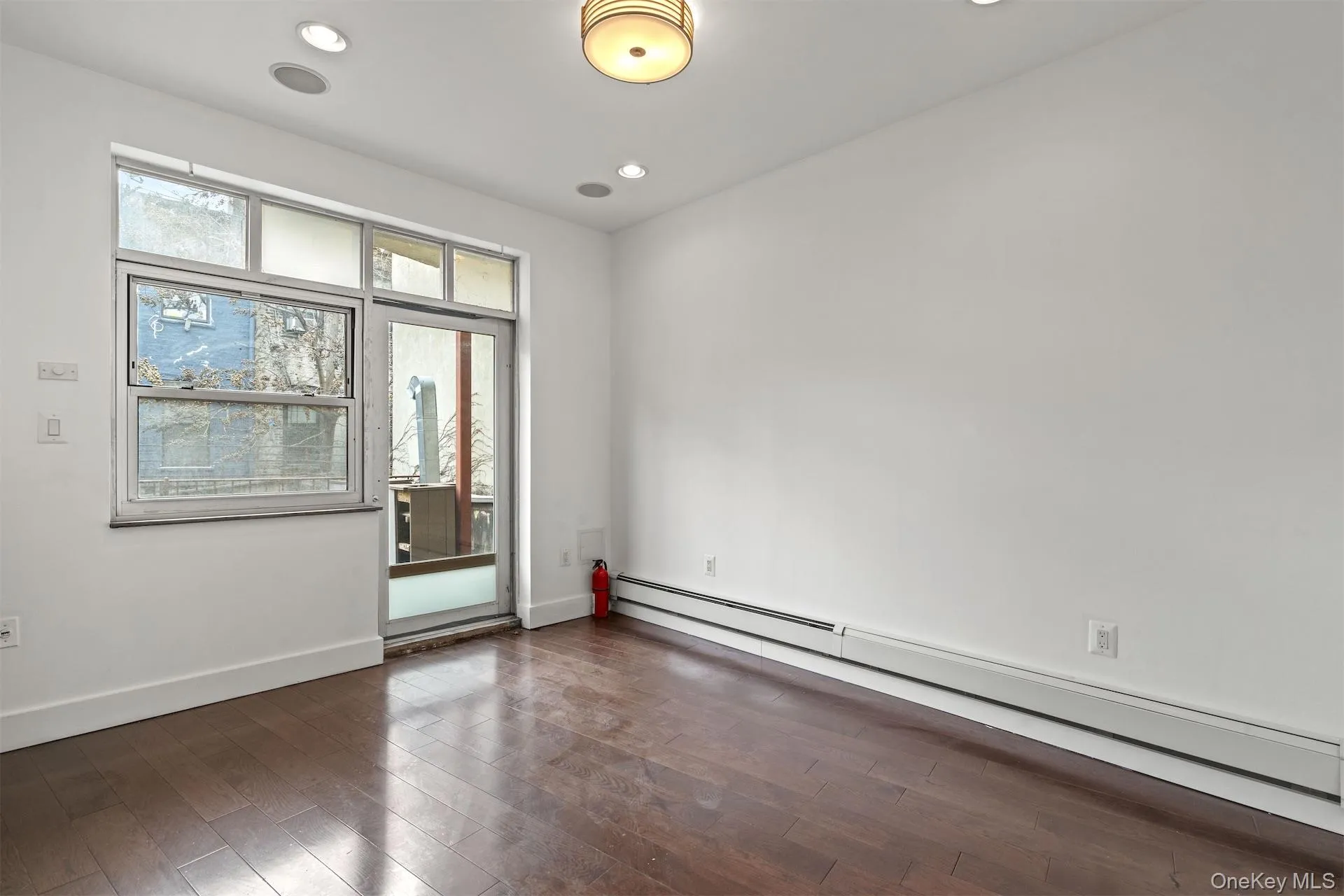 Unfurnished room featuring a baseboard radiator, dark wood-style floors, and recessed lighting Unfurnished room featuring a baseboard radiator, dark wood-style floors, and recessed lighting