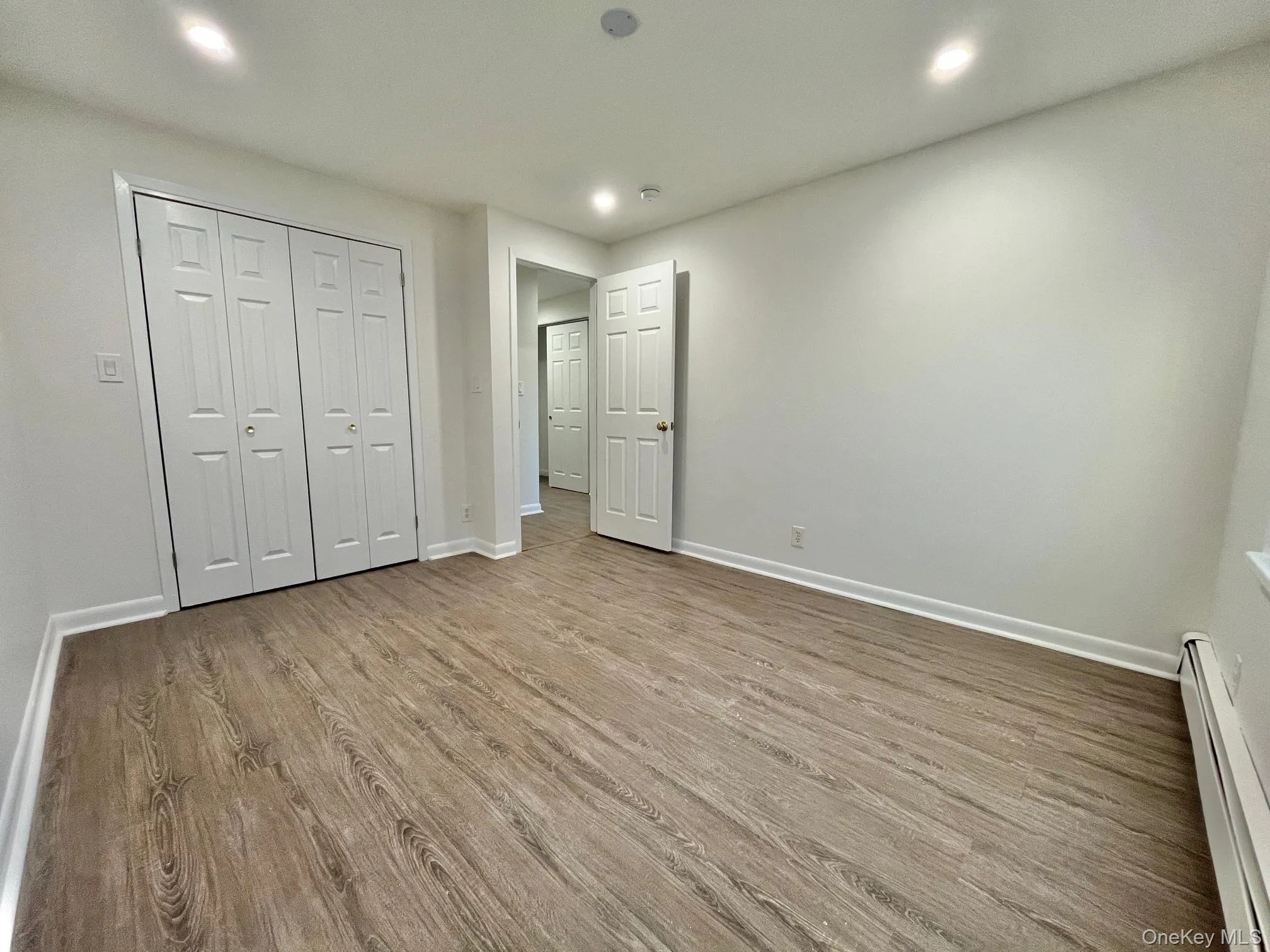 Unfurnished bedroom featuring a baseboard heating unit, wood finished floors, a closet, and recessed lighting Unfurnished bedroom featuring a baseboard heating unit, wood finished floors, a closet, and recessed lighting