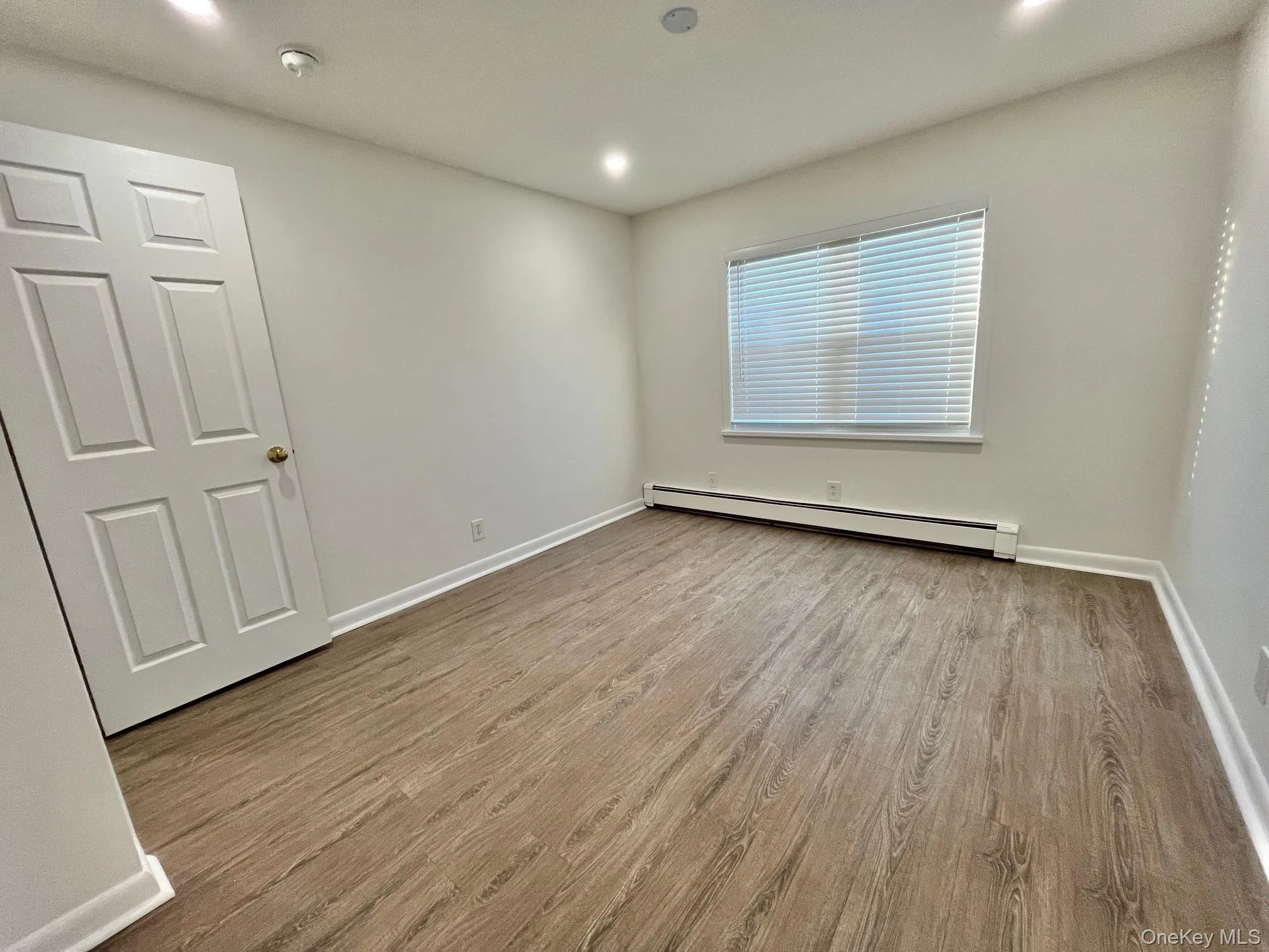 Empty room with light wood-style floors, baseboard heating, and recessed lighting Empty room with light wood-style floors, baseboard heating, and recessed lighting