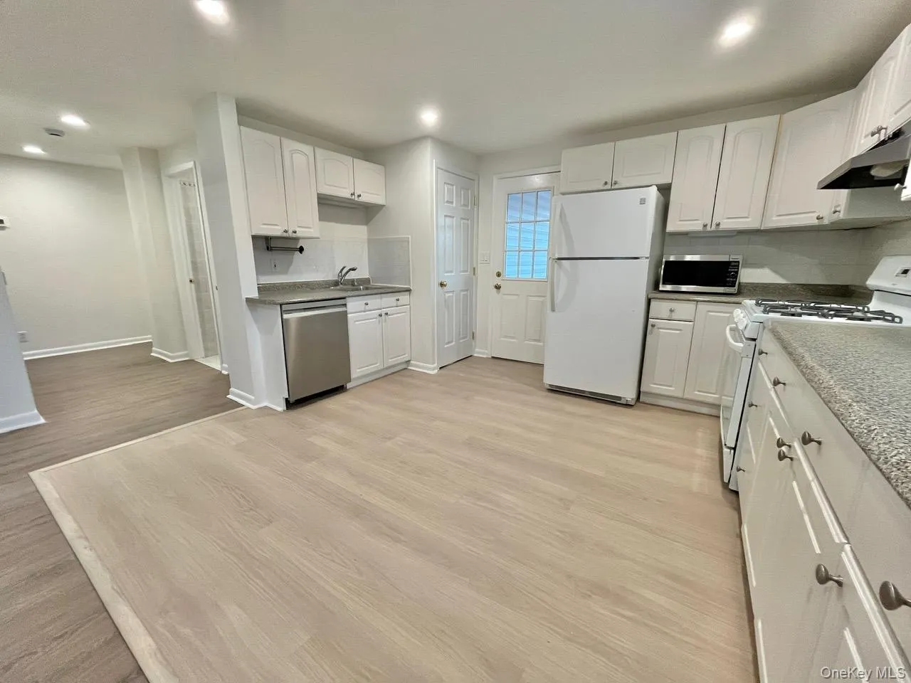 Kitchen with appliances with stainless steel finishes, white cabinetry, light wood finished floors, recessed lighting, and tasteful backsplash Kitchen with appliances with stainless steel finishes, white cabinetry, light wood finished floors, recessed lighting, and tasteful backsplash