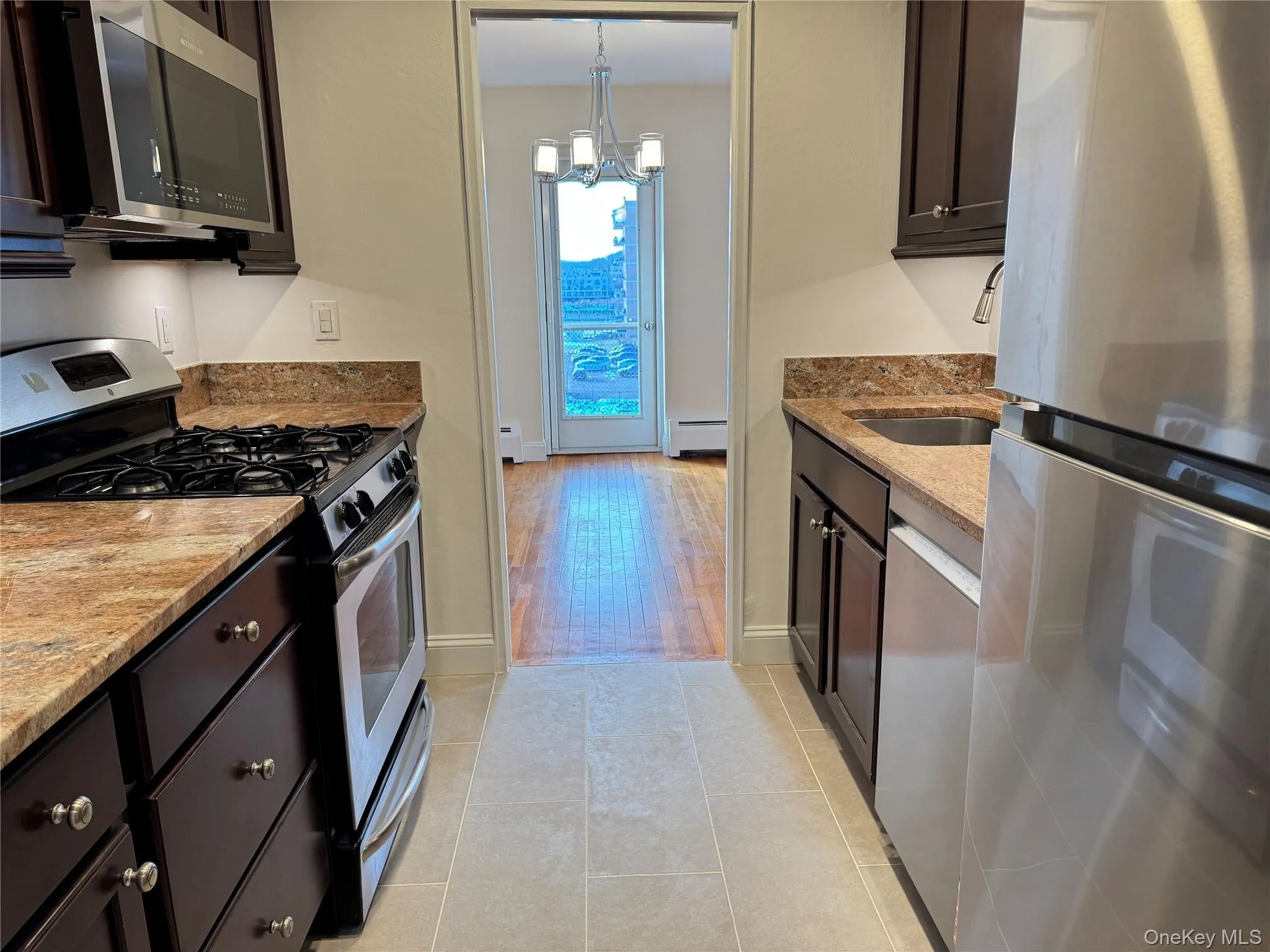 Galley Kitchen with appliances with stainless steel finishes, light stone counters, dark brown cabinets Galley Kitchen with appliances with stainless steel finishes, light stone counters, dark brown cabinets