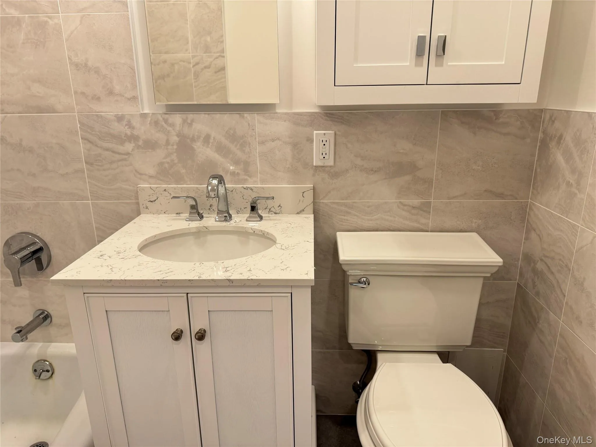 Full bath with vanity, tile walls, shower / bathtub combination, and tasteful backsplash Full bath with vanity, tile walls, shower / bathtub combination, and tasteful backsplash