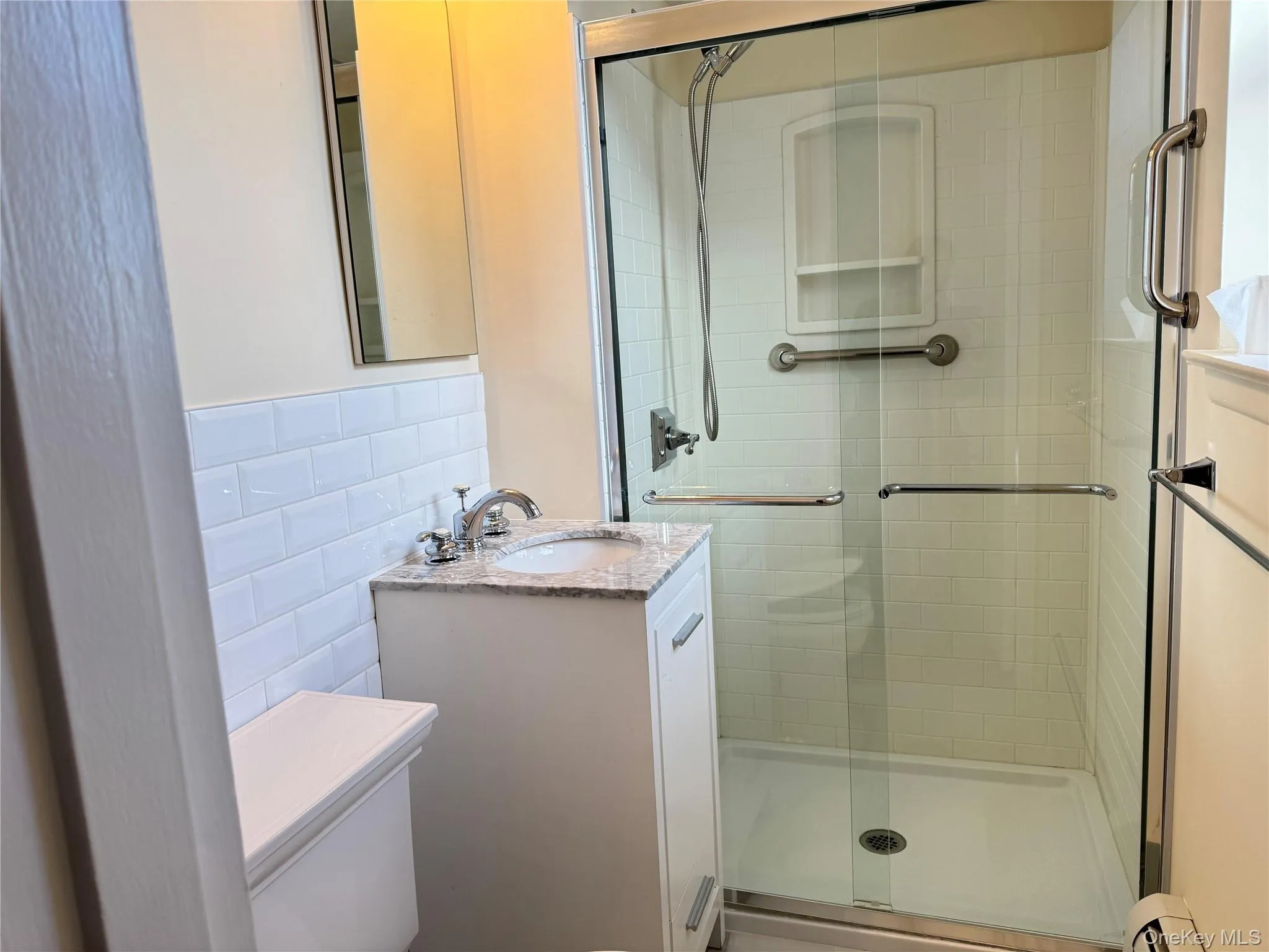 Bathroom with vanity, a shower stall, tile walls, and baseboard heating Bathroom with vanity, a shower stall, tile walls, and baseboard heating