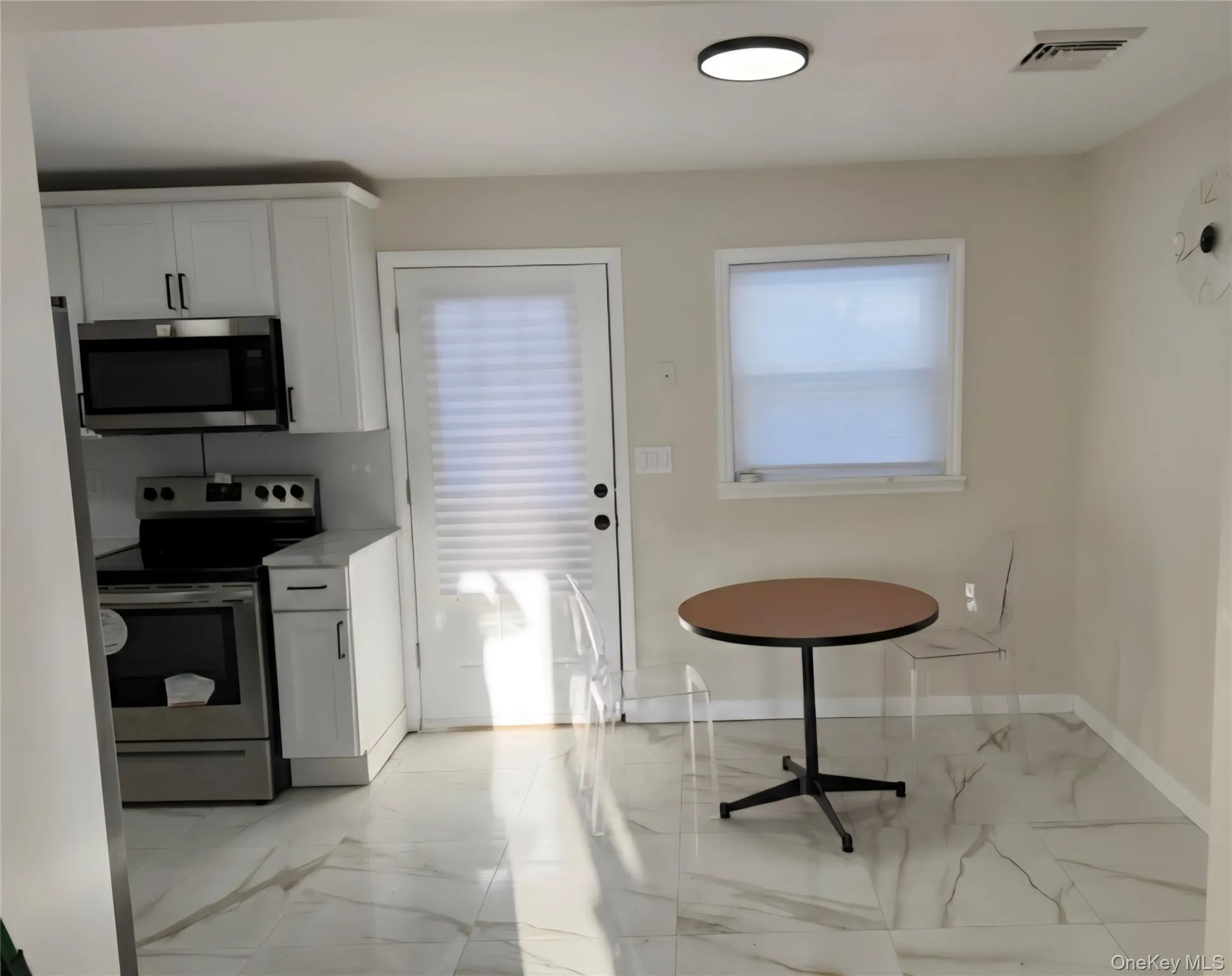 Kitchen featuring white cabinetry, appliances with stainless steel finishes, light countertops, and light marble finish flooring Kitchen featuring white cabinetry, appliances with stainless steel finishes, light countertops, and light marble finish flooring