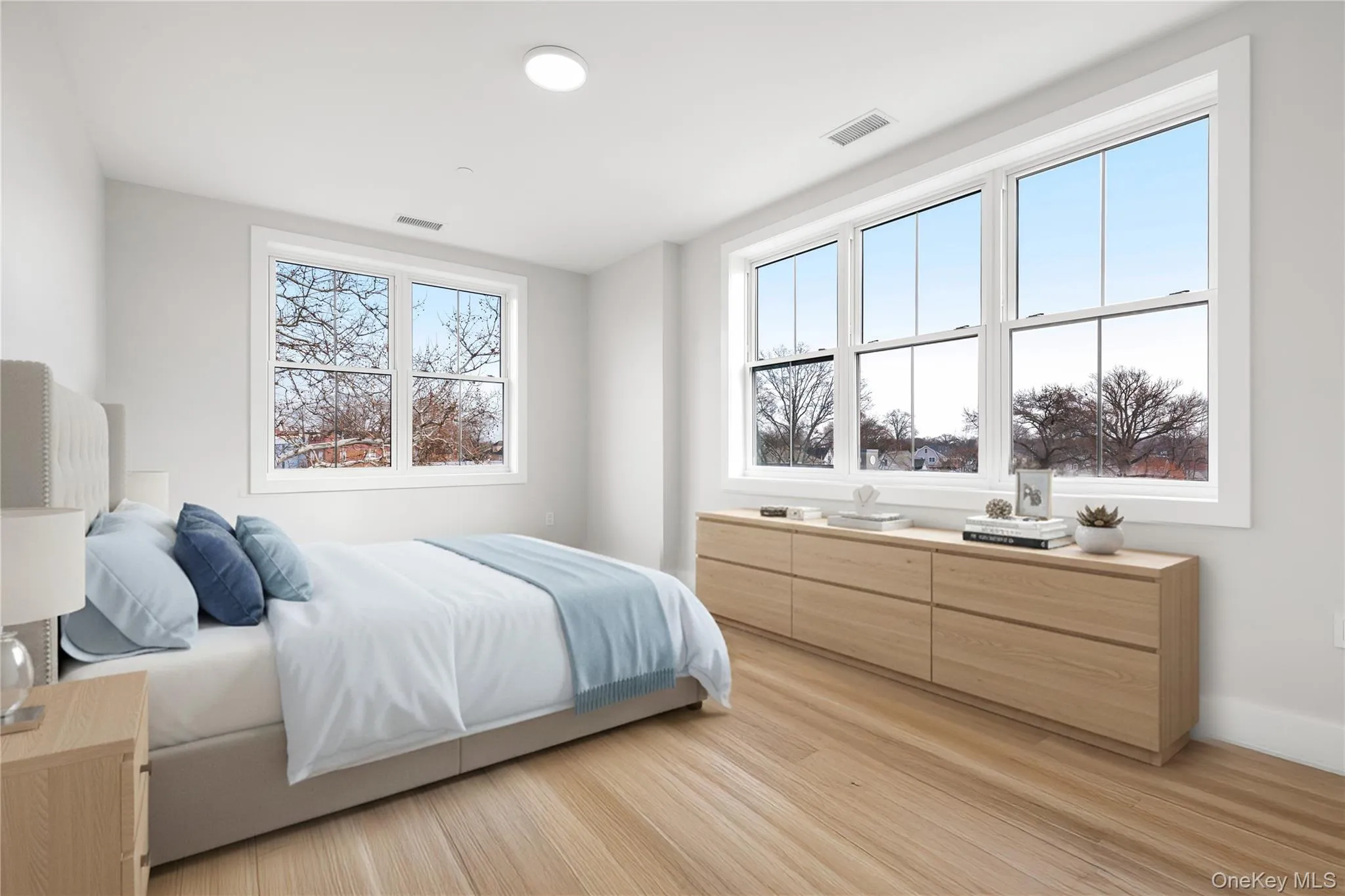 Bedroom with light wood-type flooring and multiple windows. Digitally staged. Bedroom with light wood-type flooring and multiple windows. Digitally staged.