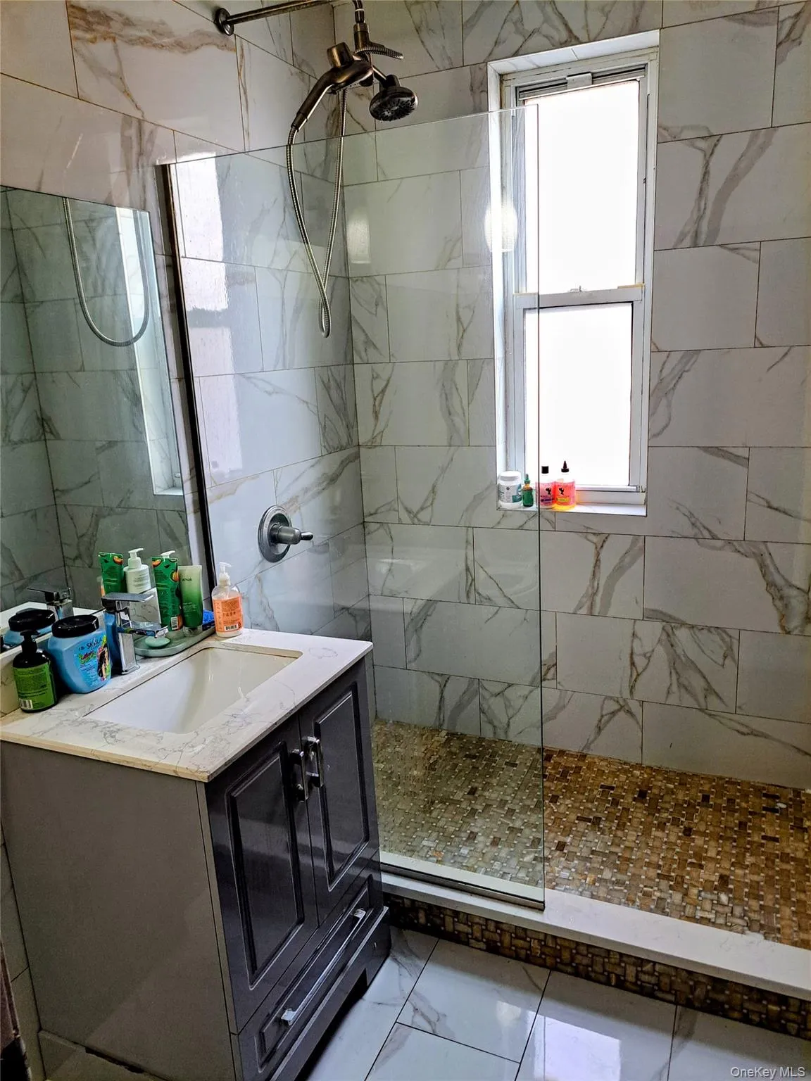 Full bathroom with walk in shower, vanity, and marble flooring Full bathroom with walk in shower, vanity, and marble flooring