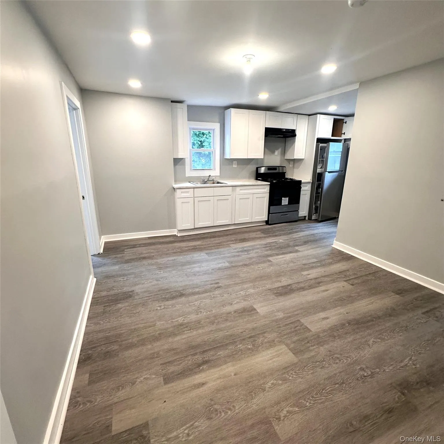 Kitchen with stainless steel and black appliances, a sink, baseboards, white cabinets, and recessed lighting, vinyl flooring Kitchen with stainless steel and black appliances, a sink, baseboards, white cabinets, and recessed lighting, vinyl flooring