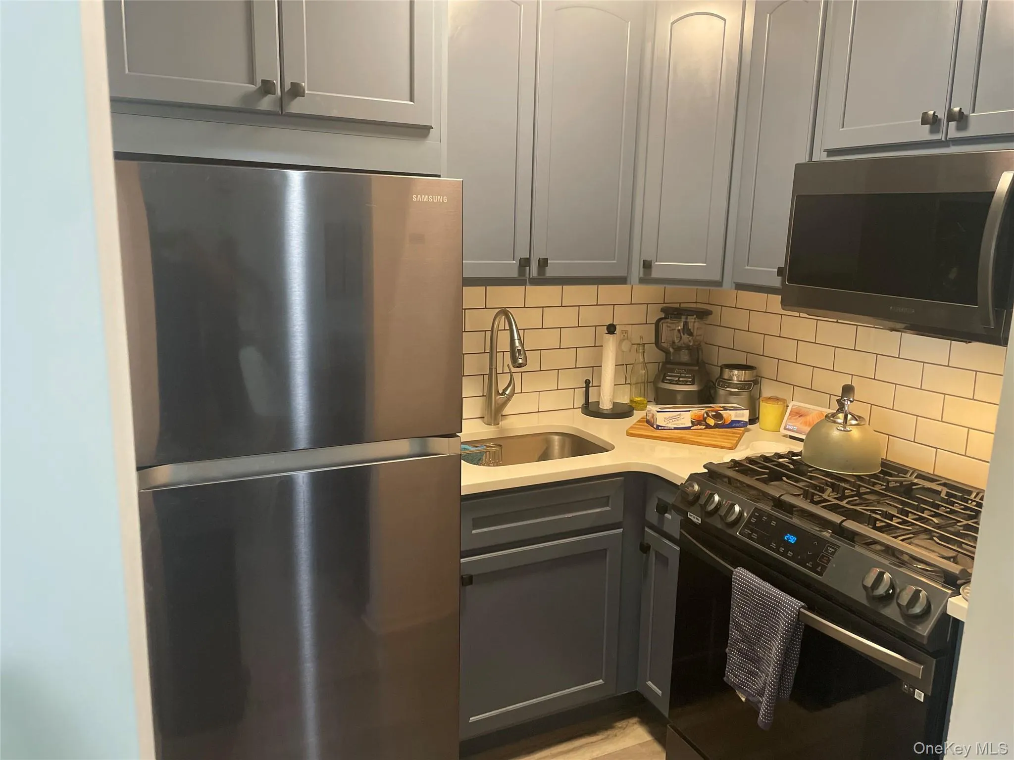 Kitchen featuring appliances with stainless steel finishes, a sink, decorative backsplash, and light countertops Kitchen featuring appliances with stainless steel finishes, a sink, decorative backsplash, and light countertops